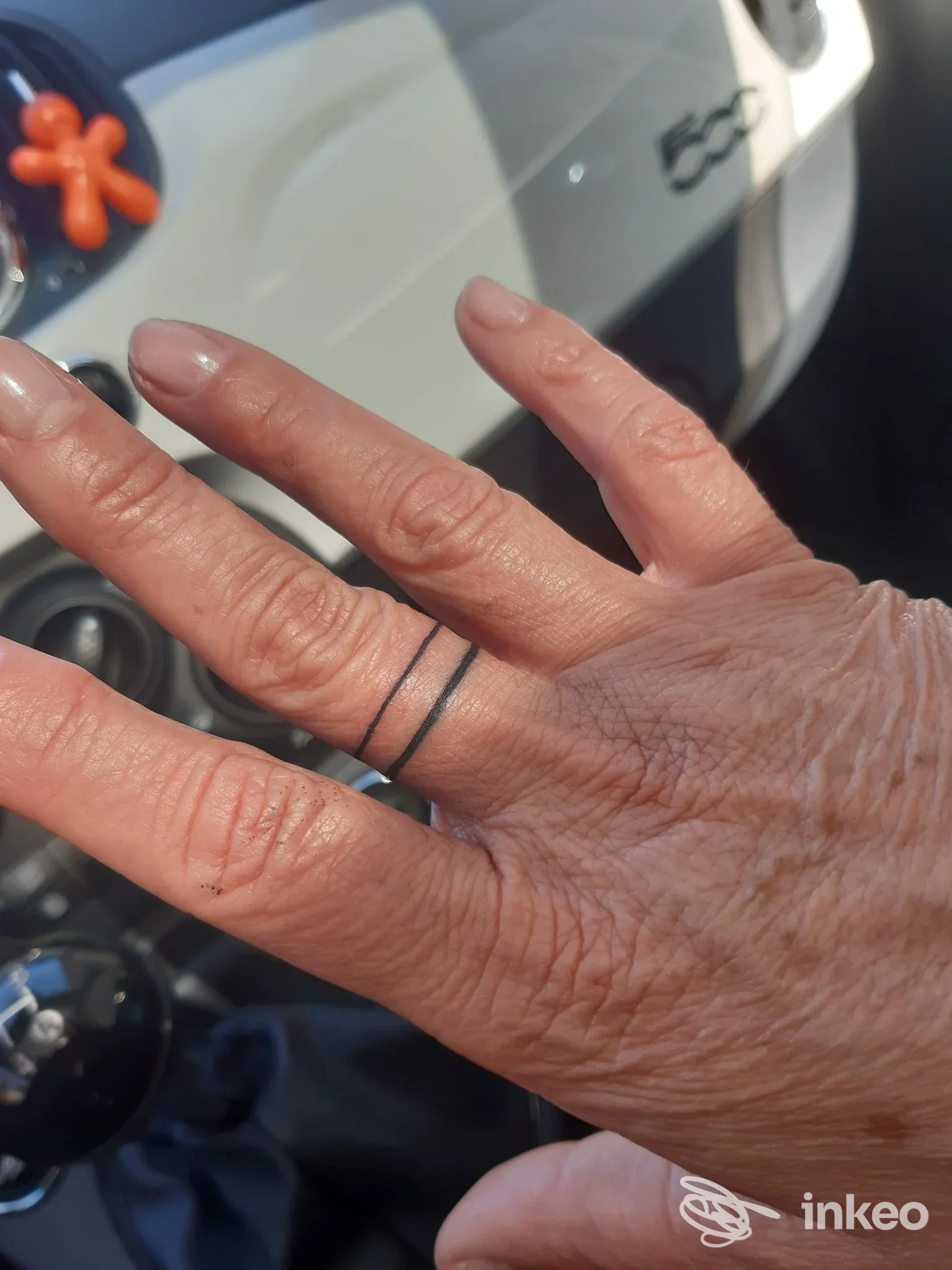 Due sottili anelli tatuati sul dito di una mano, fotografati in auto — immagine di Mad Ink Tattoo, Simaxis.