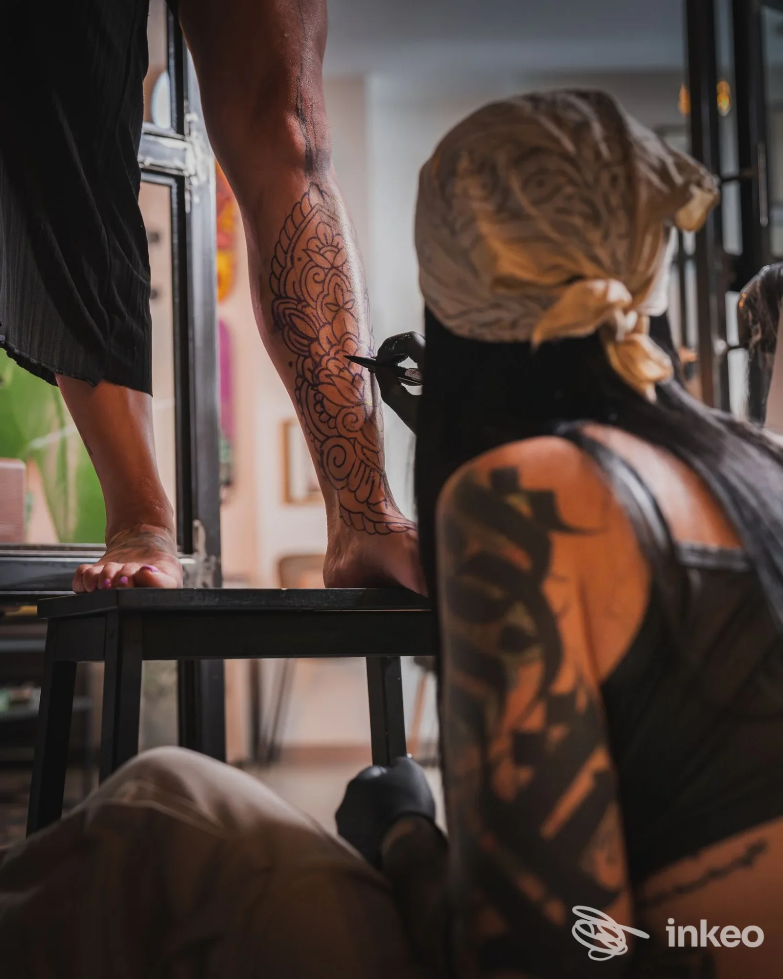 Artista al lavoro su un tatuaggio a linee floreali sul polpaccio, foto fornita da NUMB Tattoo Parlour, Porto Torres.