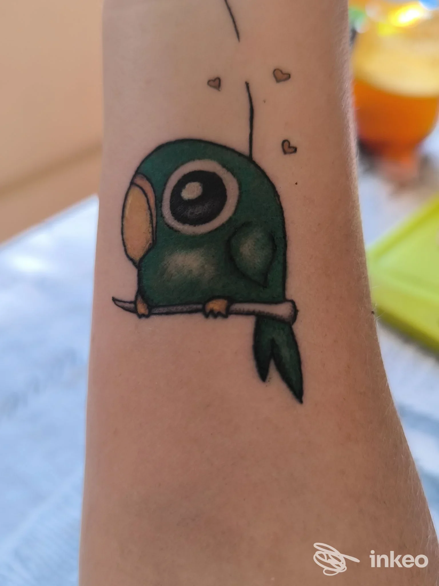 Tatuaggio su avambraccio raffigurante un uccellino verde stilizzato. Pirro Tattoo Studio, Quartu Sant'Elena.