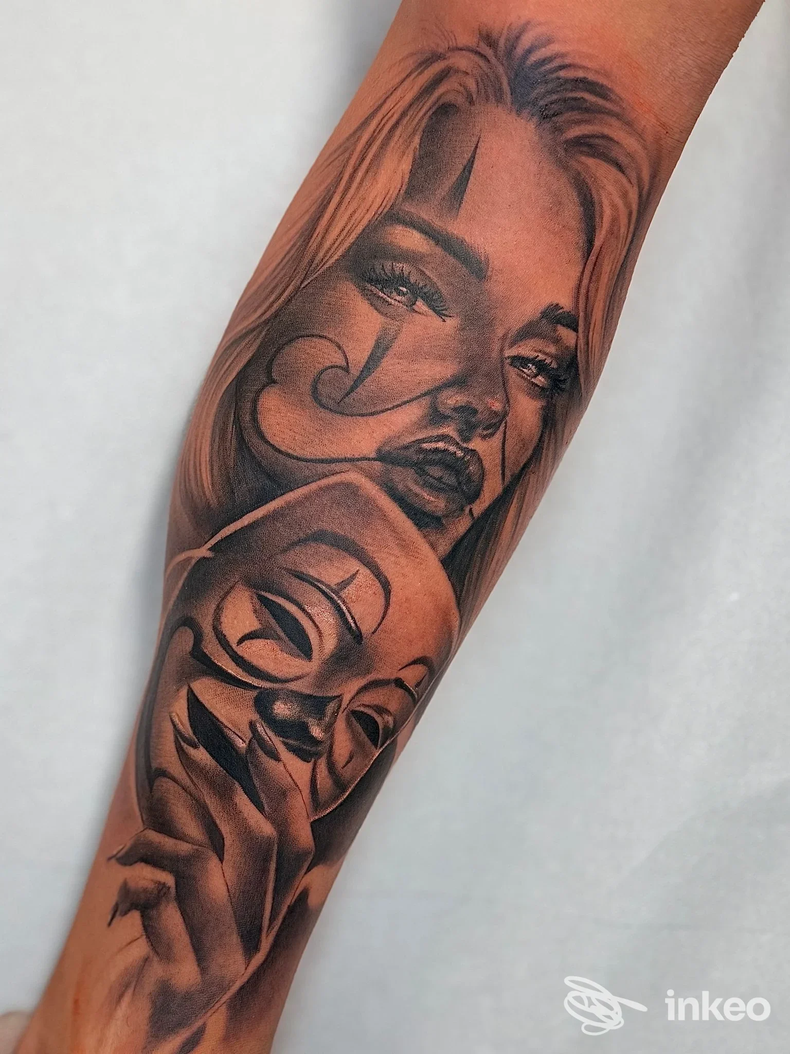 Tatuaggio realistico su avambraccio con ritratti femminili e una maschera, opera condivisa da Pirro Tattoo Studio a Quartu Sant'Elena.