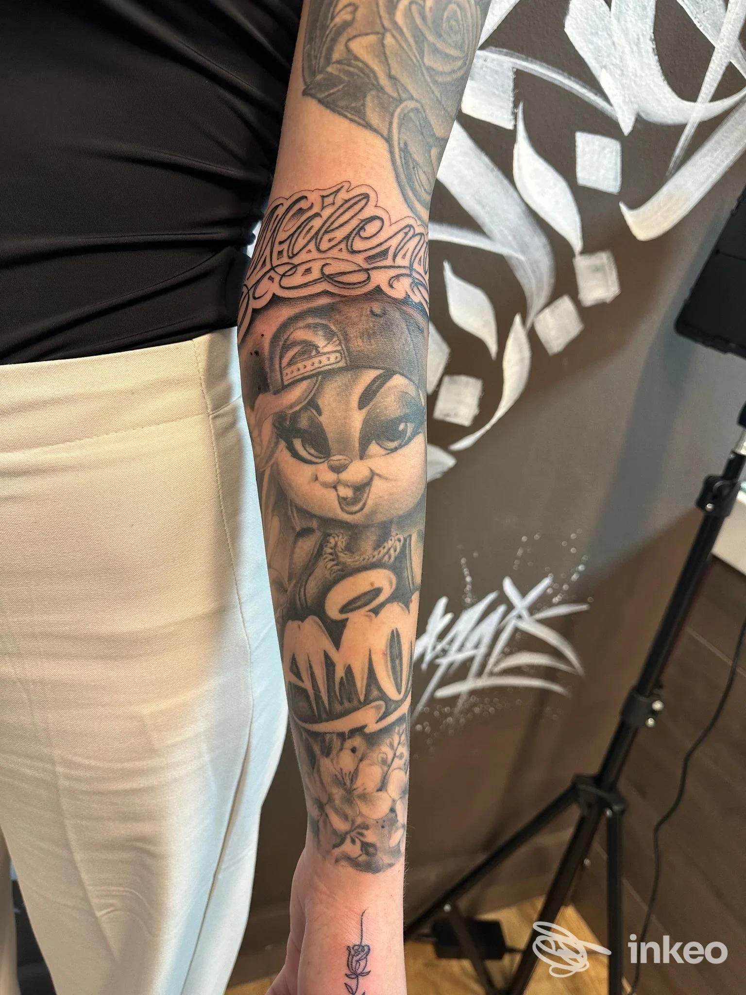 Primo piano di un tatuaggio a manica sull'avambraccio con personaggio cartoon in black & grey, realizzato da Rado Tattoo a Sassari.