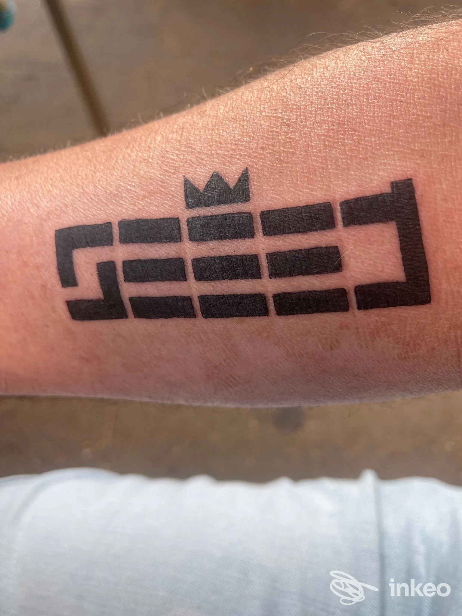 Primo piano di un tatuaggio nero geometrico sull'avambraccio, scattato in studio; Rebis Tattoo di Sara Pushi, Sassari.
