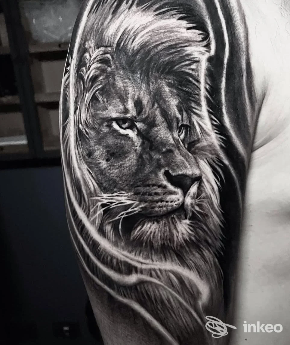 Tatuaggio realistico in bianco e nero di un leone sul braccio di una persona, eseguito da Soffitta Tattoo Studio, visibile in primo piano sulla pelle.
