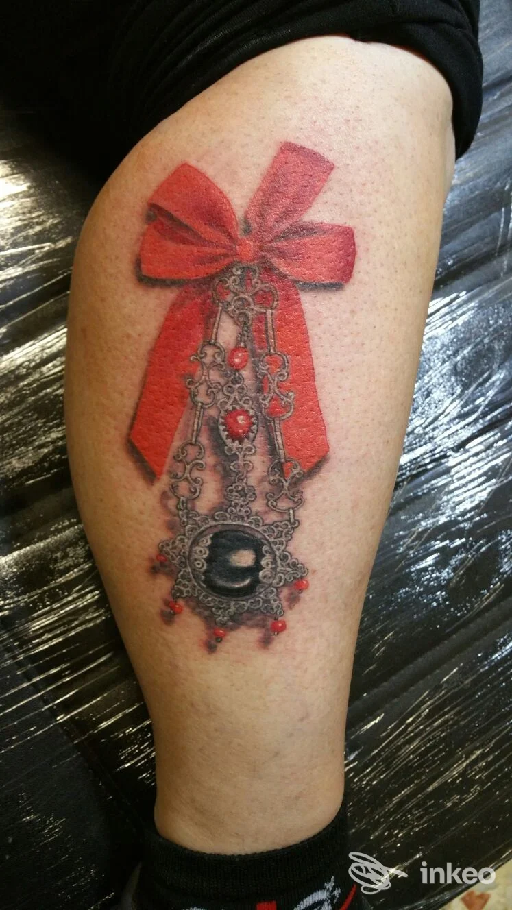Tatuaggio ornamentale con fiocco rosso sul polpaccio, Scorpiontattoo, Sassari.