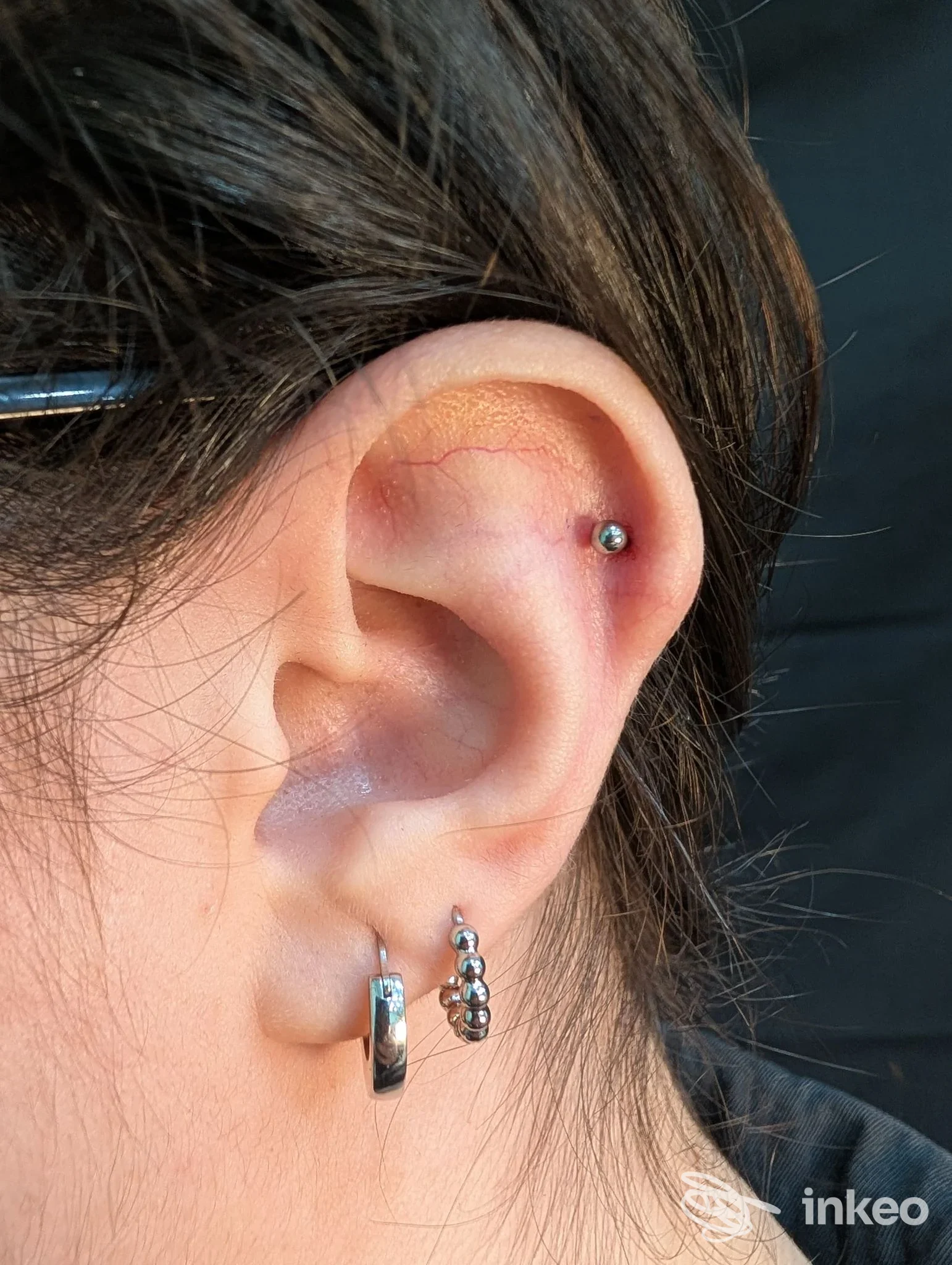 Primo piano di un orecchio con piercing al trago e due orecchini al lobo, foto per 800A tattoo&piercing a Palermo.