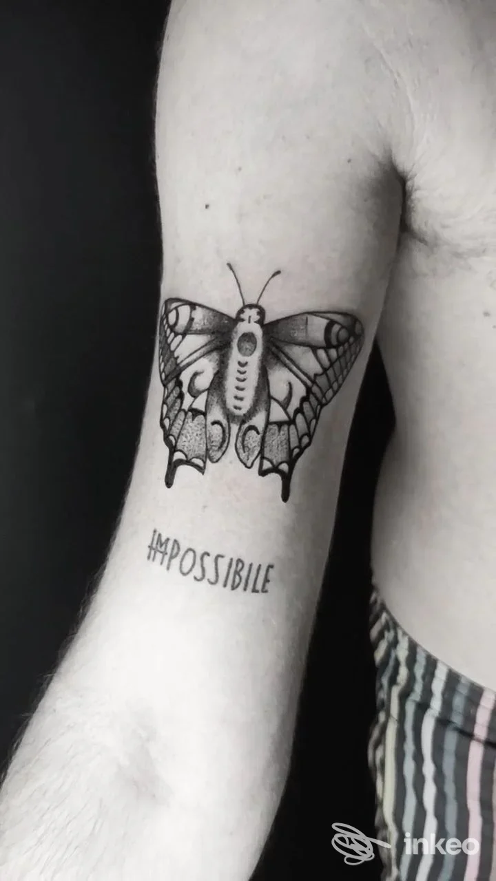 Primo piano di un tatuaggio farfalla e la parola 'IMPOSSIBLE' sull'avambraccio, lavoro fotografato per ART GALLERY.INK TATTOO, Sambuca di Sicilia.