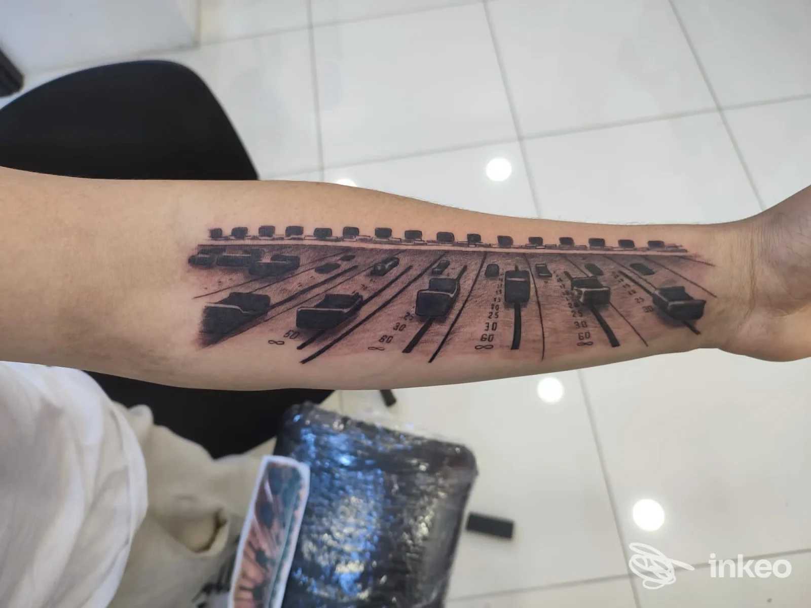 Tatuaggio su avambraccio raffigurante fader di una console audio, scattato presso Amon Tattoo & Piercing a Ragusa.
