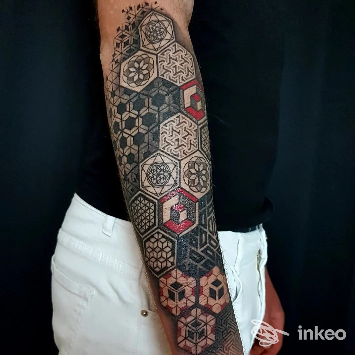 Avambraccio tatuato con motivi geometrici esagonali in nero e rosso, lavoro realizzato da Aurea Tattoo a Santa Ninfa.