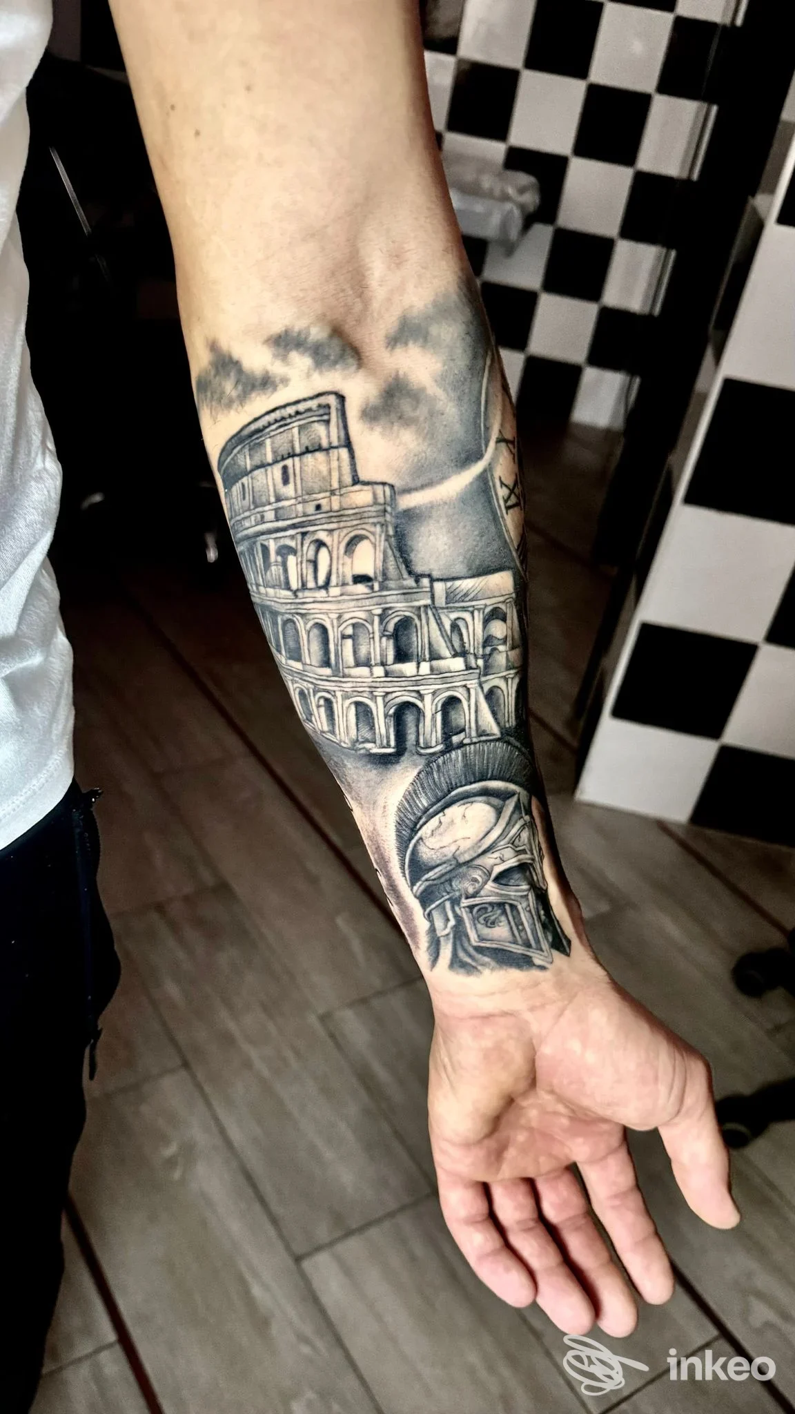 Avambraccio con tatuaggio realistico in bianco e nero del Colosseo e un elmo romano, fotografia di Art Studio Tattoo a Palermo.
