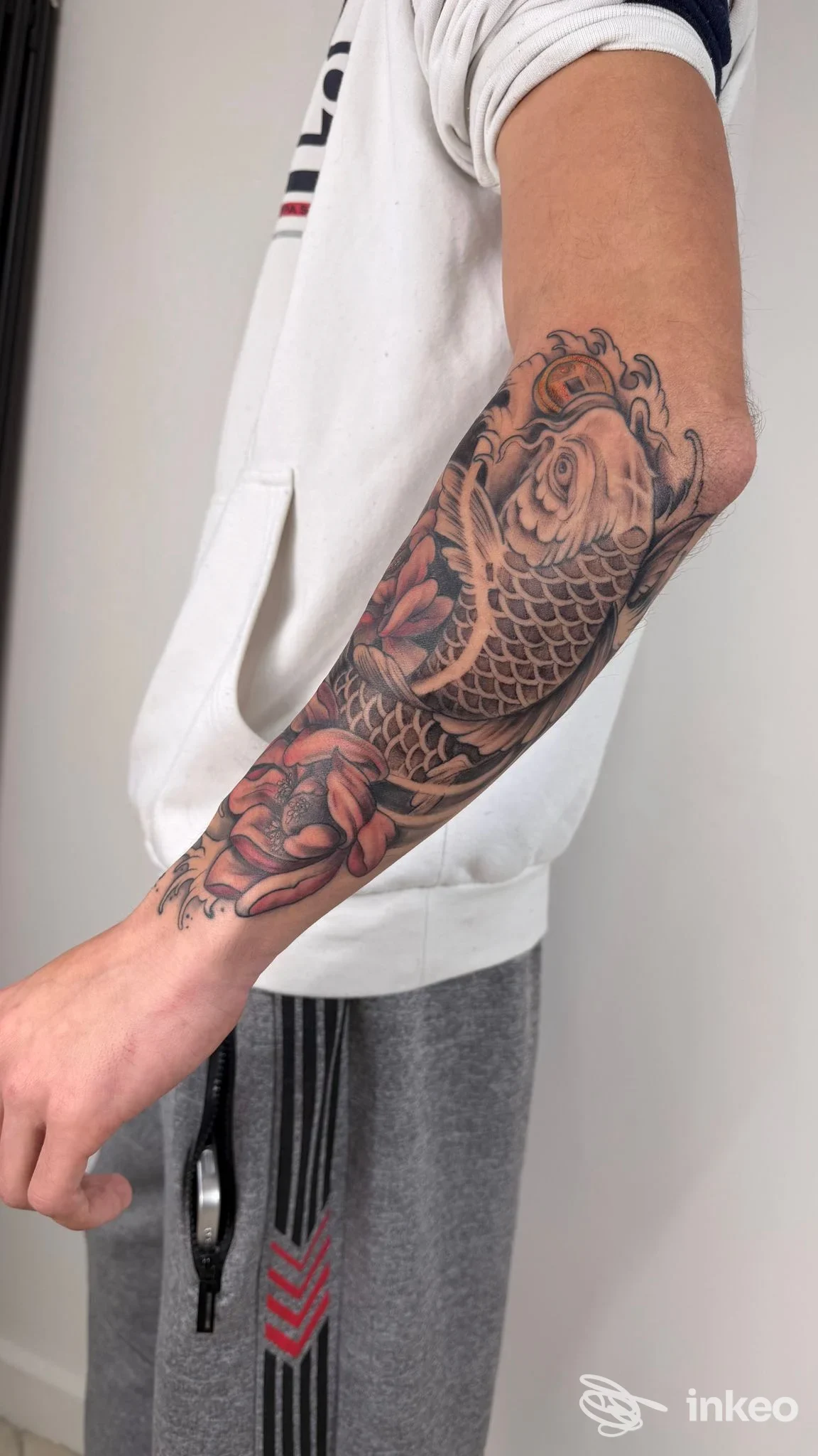 Manica parziale con carpa e fiori sull'avambraccio, fotografia di Begi TATTOO a Sciacca.