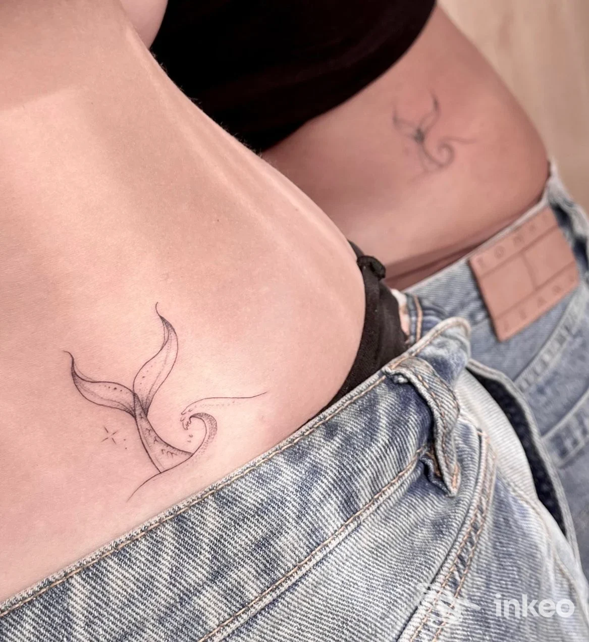 Due piccoli tatuaggi a linee sottili sul fianco/abdome visibili su pelle vicino ai jeans. Begi TATTOO, Sciacca.
