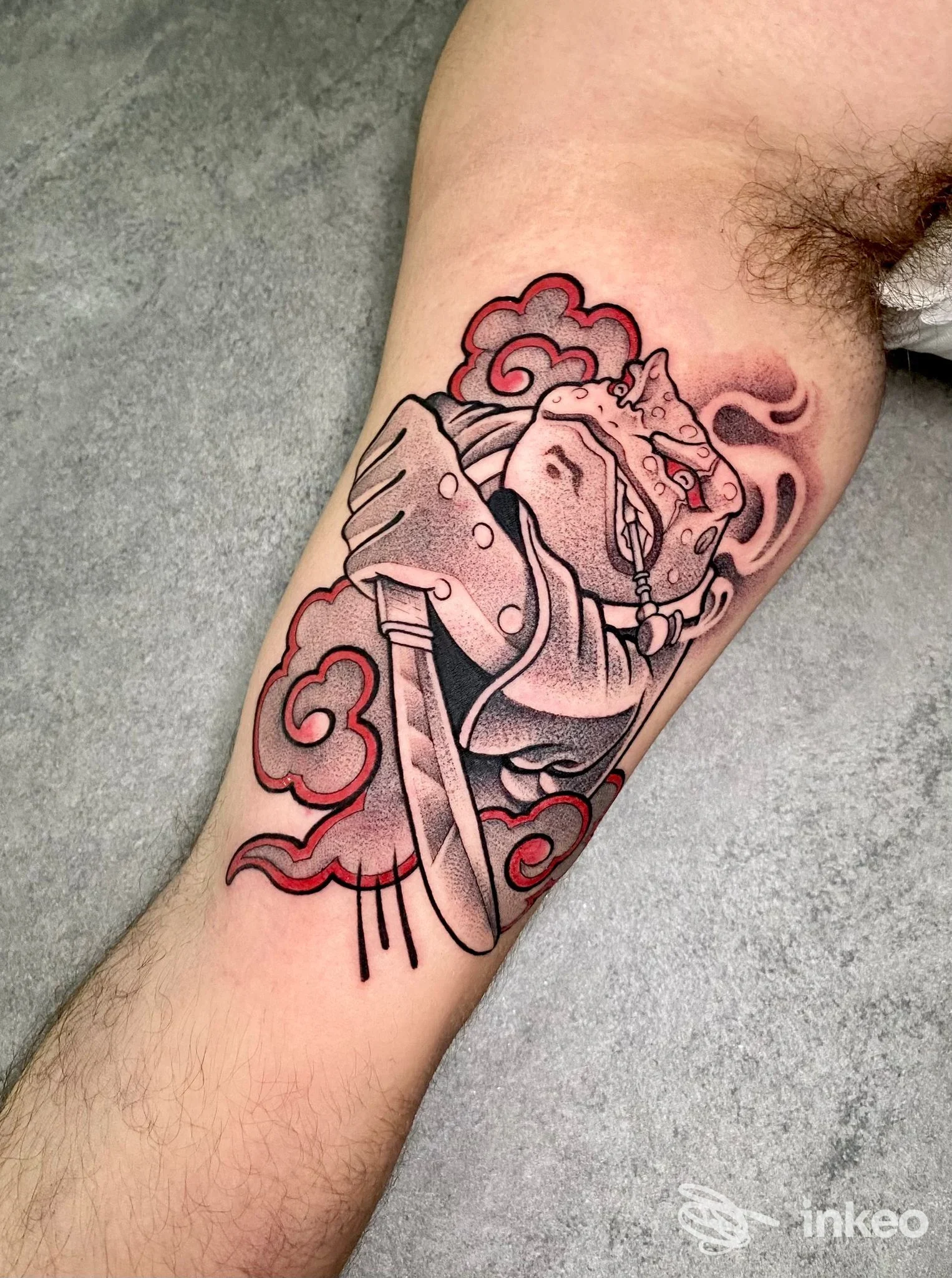 Tattoo su braccio interno raffigurante figura mascherata con pugnale e nuvole rosse, realizzato da Black Manta Tattoo a Palermo.