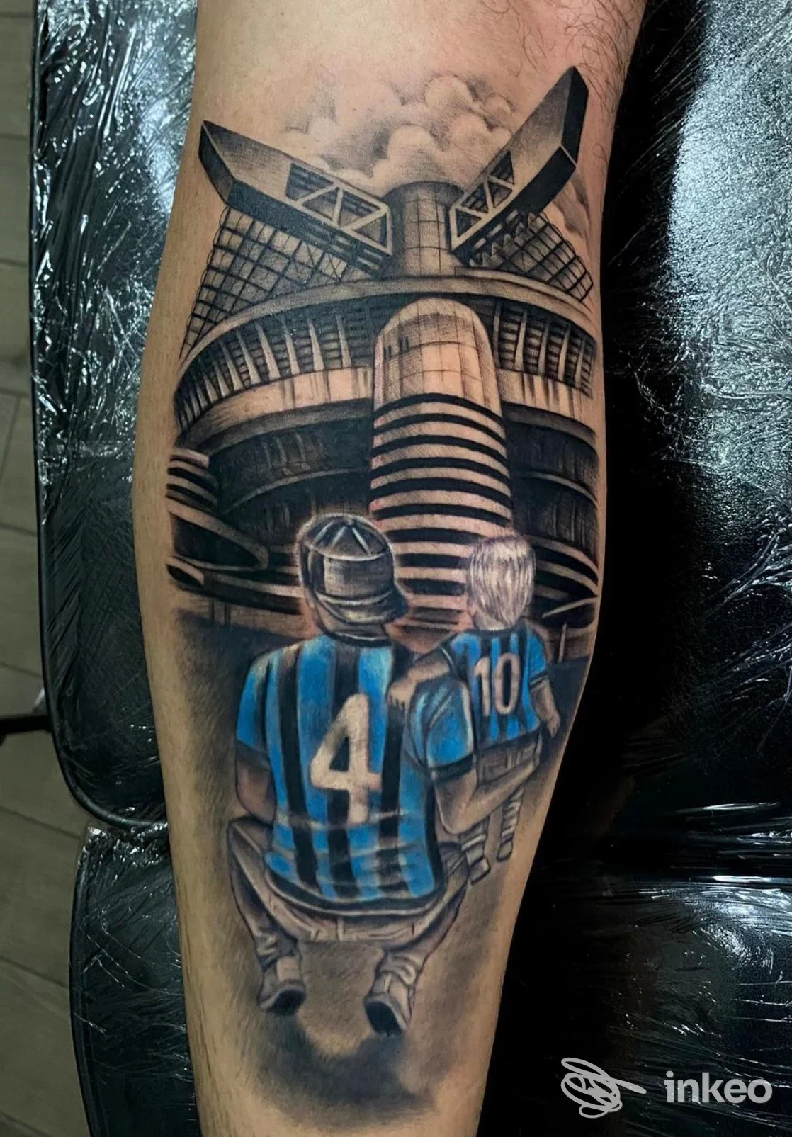 Tatuaggio realistico su avambraccio con stadio e due tifosi con le maglie 4 e 10, Black Manta Tattoo, Palermo.