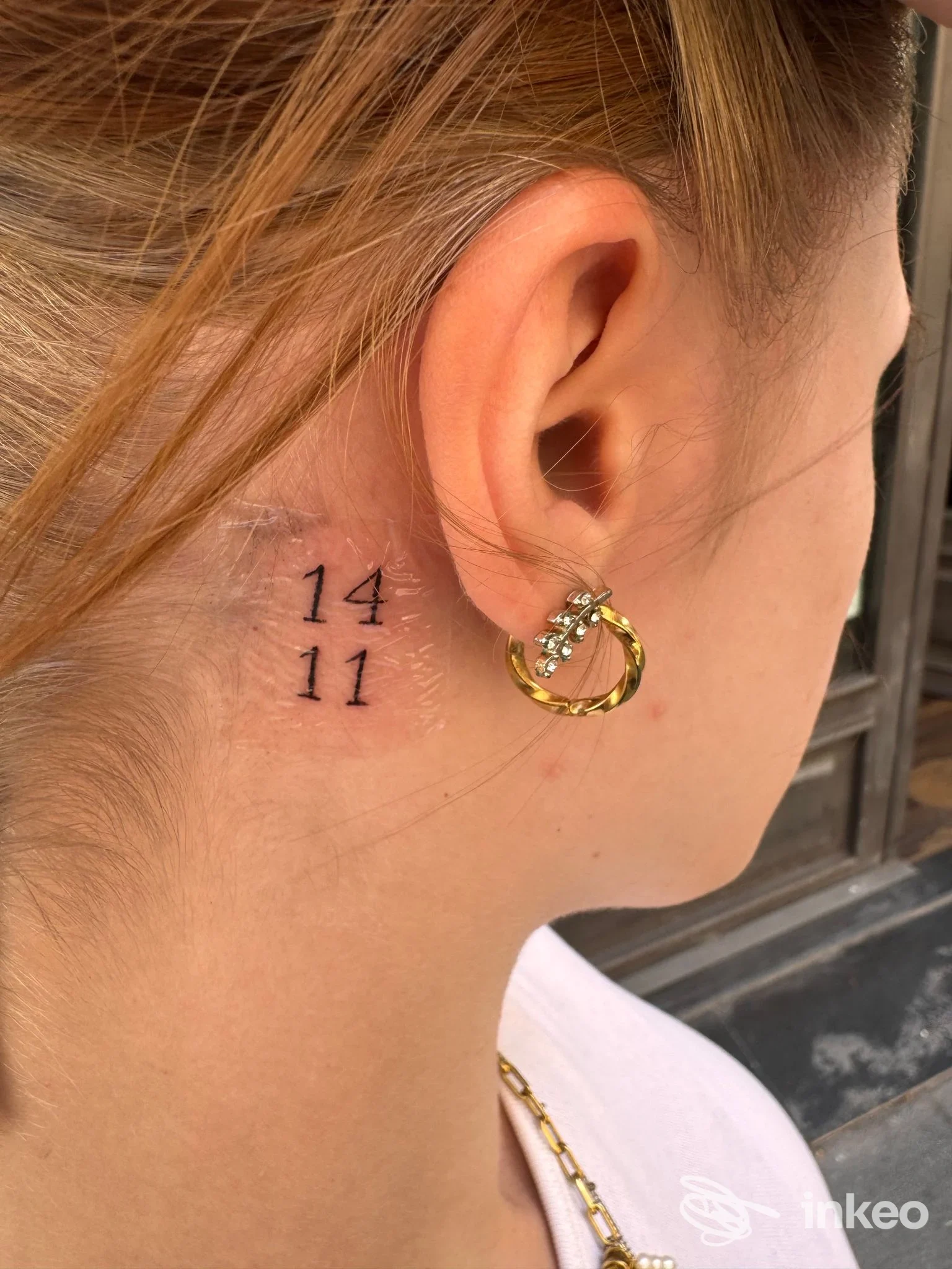 Piccolo tatuaggio numerico dietro l'orecchio destro, eseguito da Black Tower Tattoo a Catania.