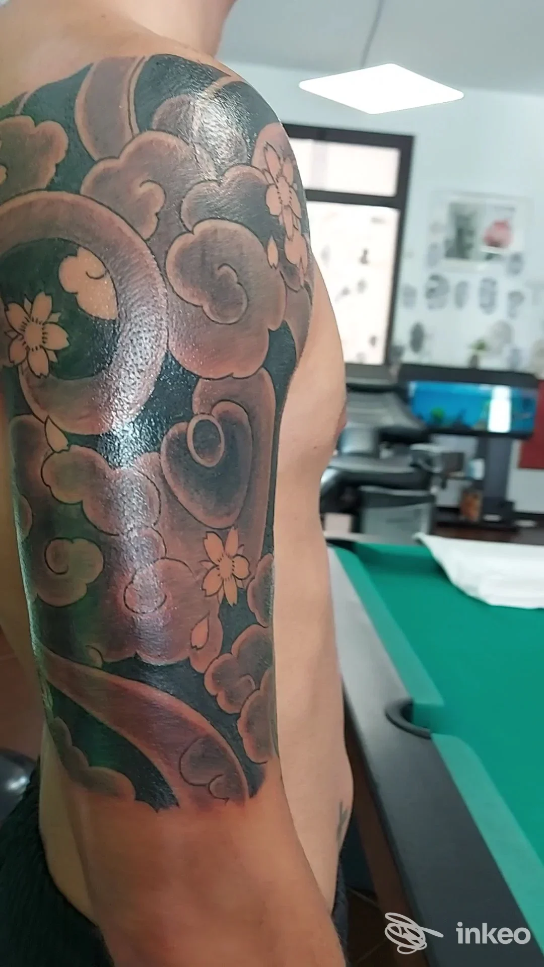 Mezza manica su spalla e alto braccio con motivo a nuvole e fiori, foto fornita da Carlos Villena Tattoo Studio, Bagheria.