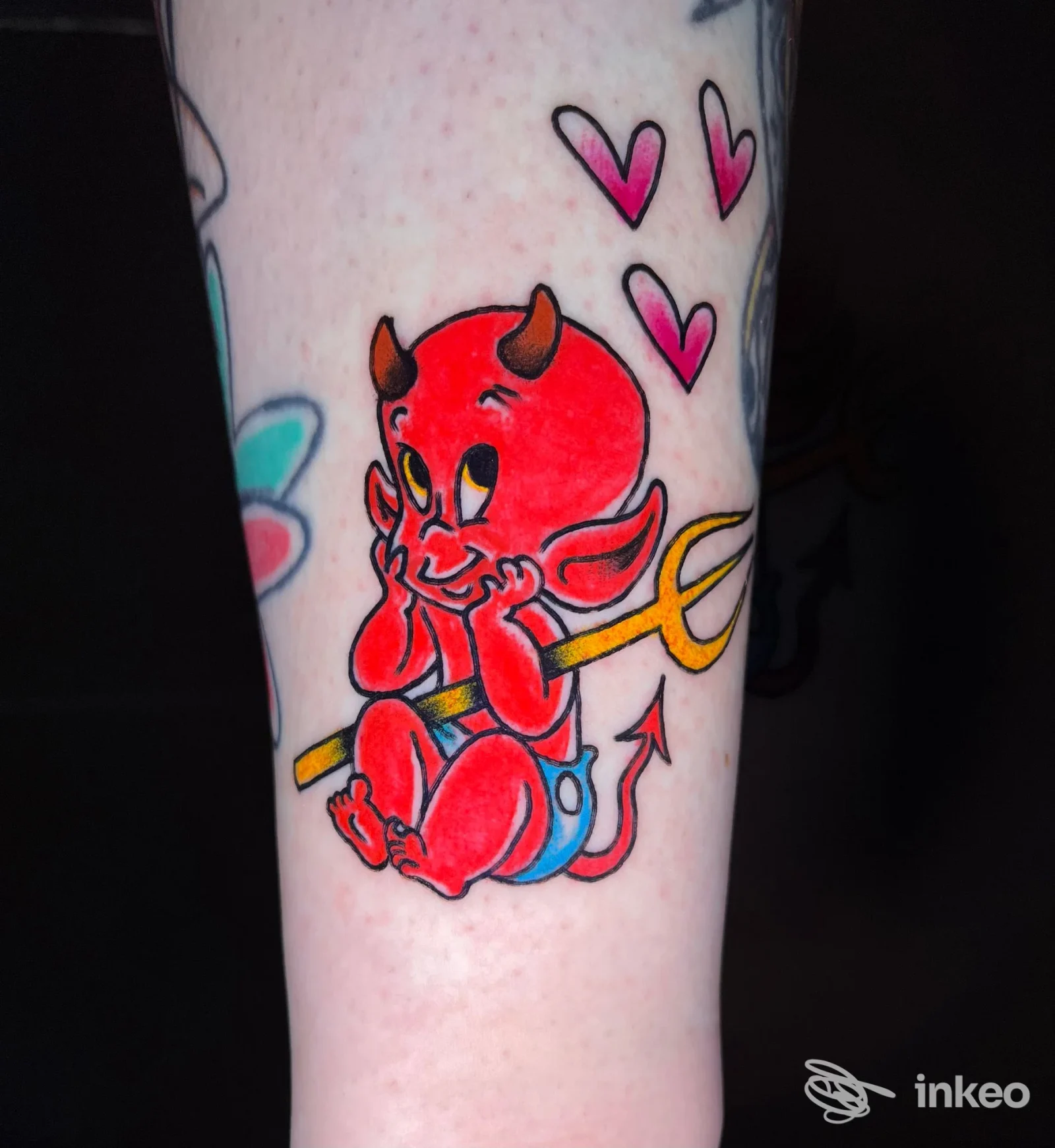 Tatuaggio su avambraccio raffigurante un piccolo diavolo rosso con tridente e cuori, lavoro di Deds tattoo, Catania.
