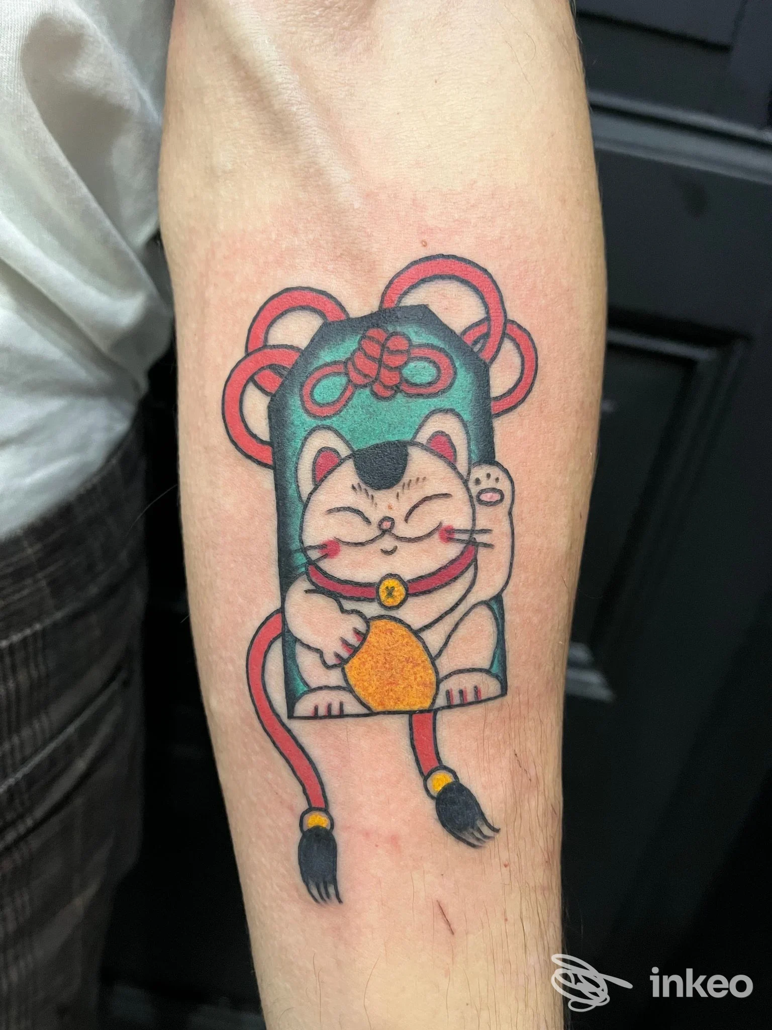Tatuaggio maneki-neko colorato sull'avambraccio, realizzato da Deds tattoo a Catania, linee nette e colori pieni.