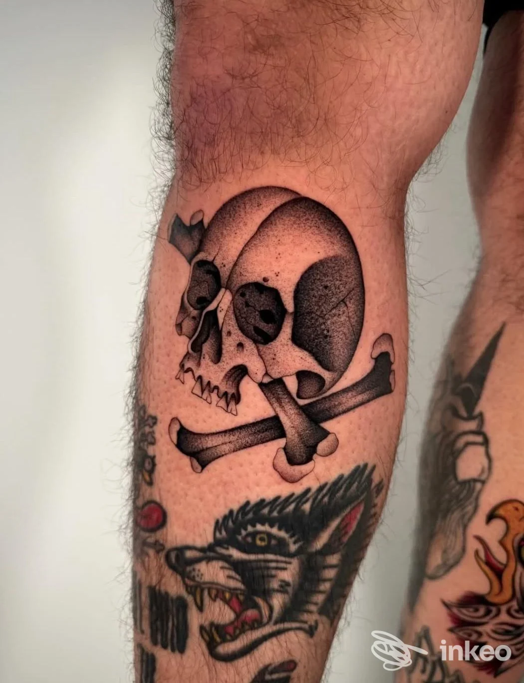 Tatuaggio di teschio con ossa incrociate e muso di lupo sul polpaccio, Blacktop Tattoo Club, Palermo.