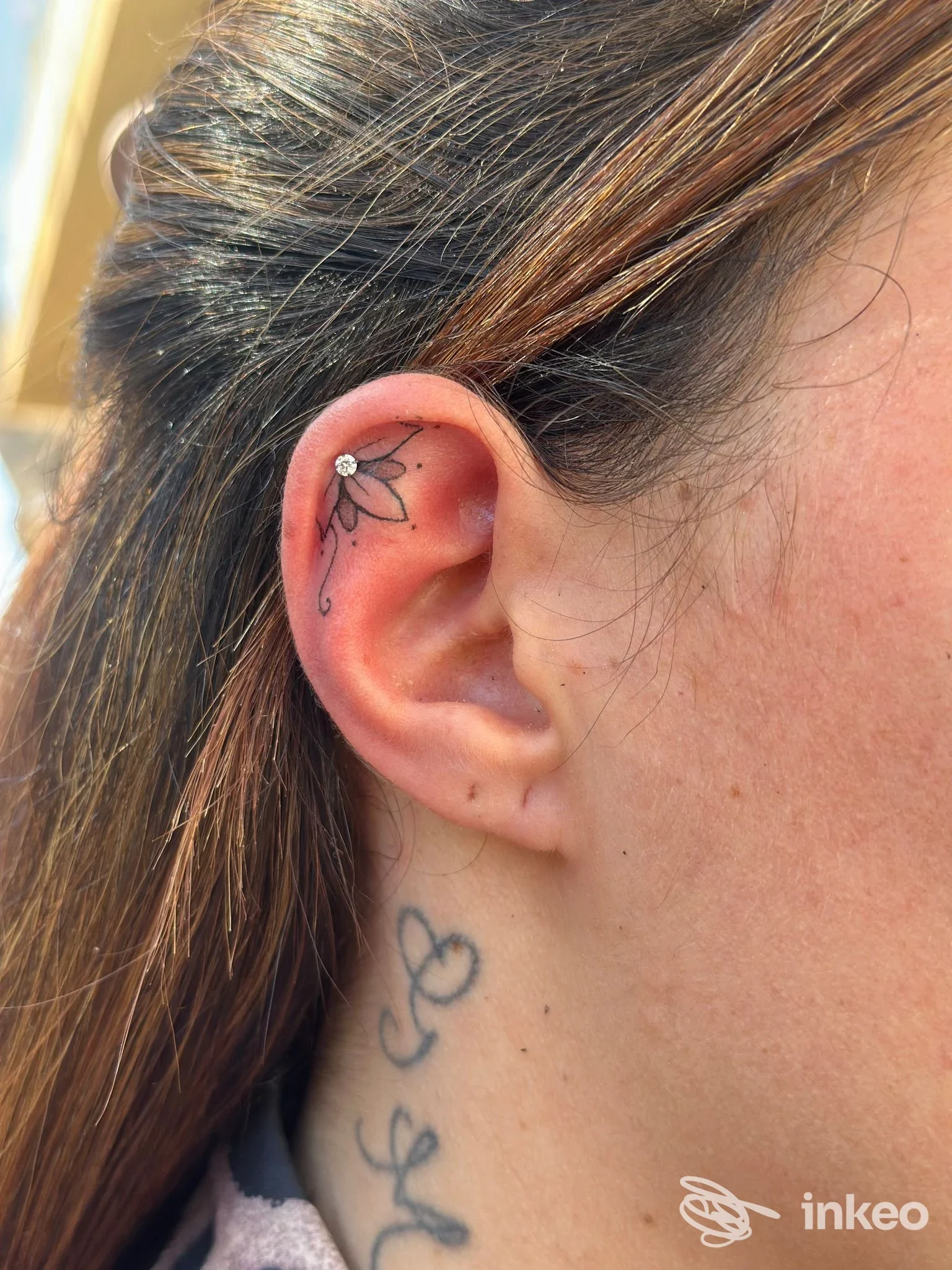 Primo piano di un piccolo tatuaggio floreale nell'orecchio destro. FLO TATTOO ART di Floriana Marino, Mazara del Vallo.