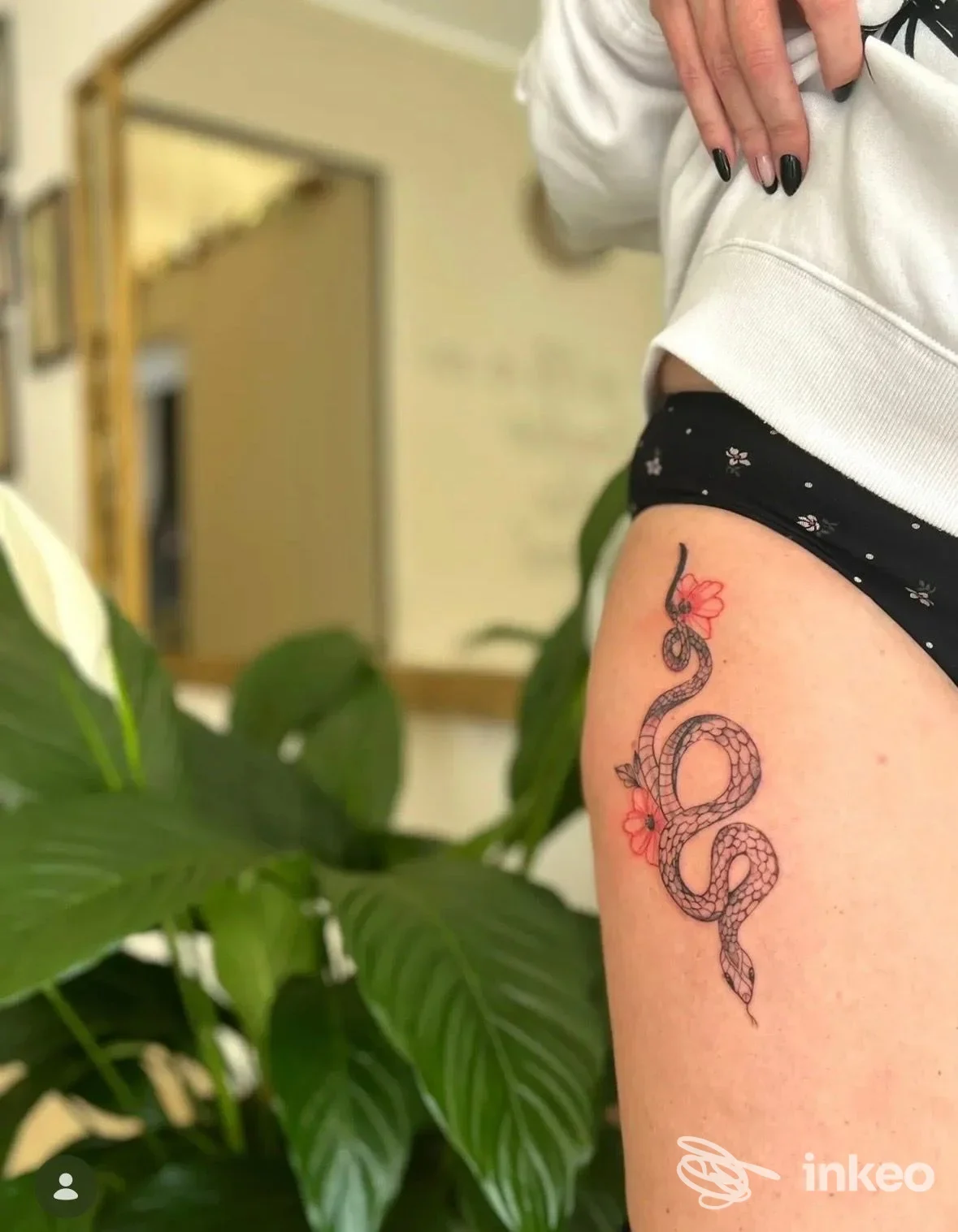 Tatuaggio a serpente nero con fiori rossi sulla coscia, fotografato in studio. FLO TATTOO ART di Floriana Marino, Mazara del Vallo.
