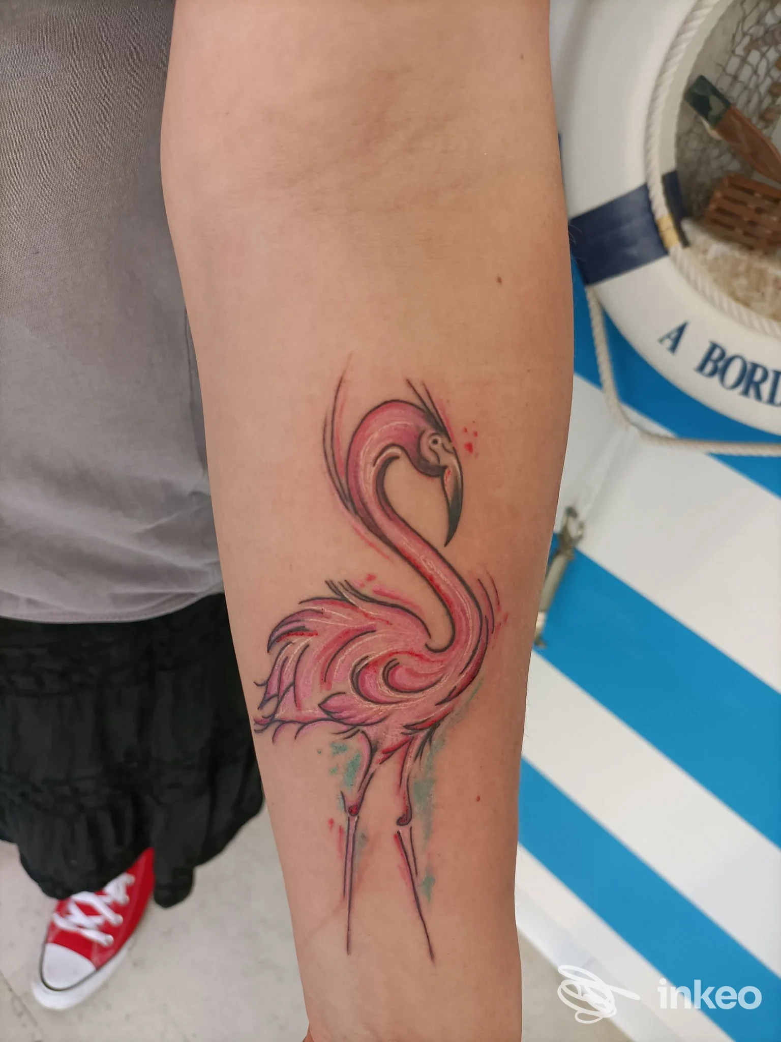 Tattoo realizzato sull’avambraccio sinistro: fenicottero stilizzato in stile acquerello rosa/rosso, con linee morbide e sfumature, su pelle scoperta.