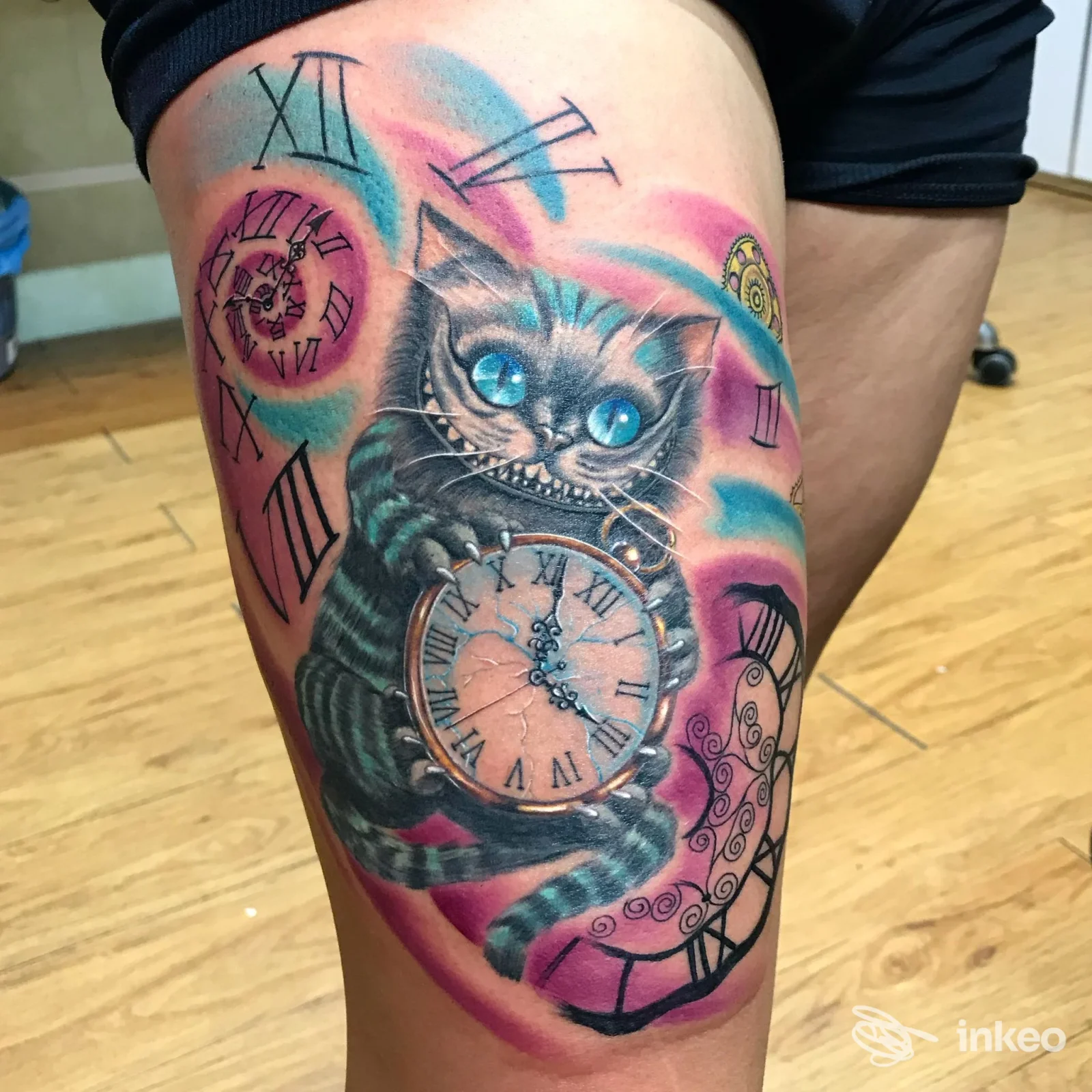Tatuaggio colorato su coscia con gatto stilizzato dagli occhi blu che stringe un orologio da tasca; immagine per Del Popolo Tattoo, Messina.