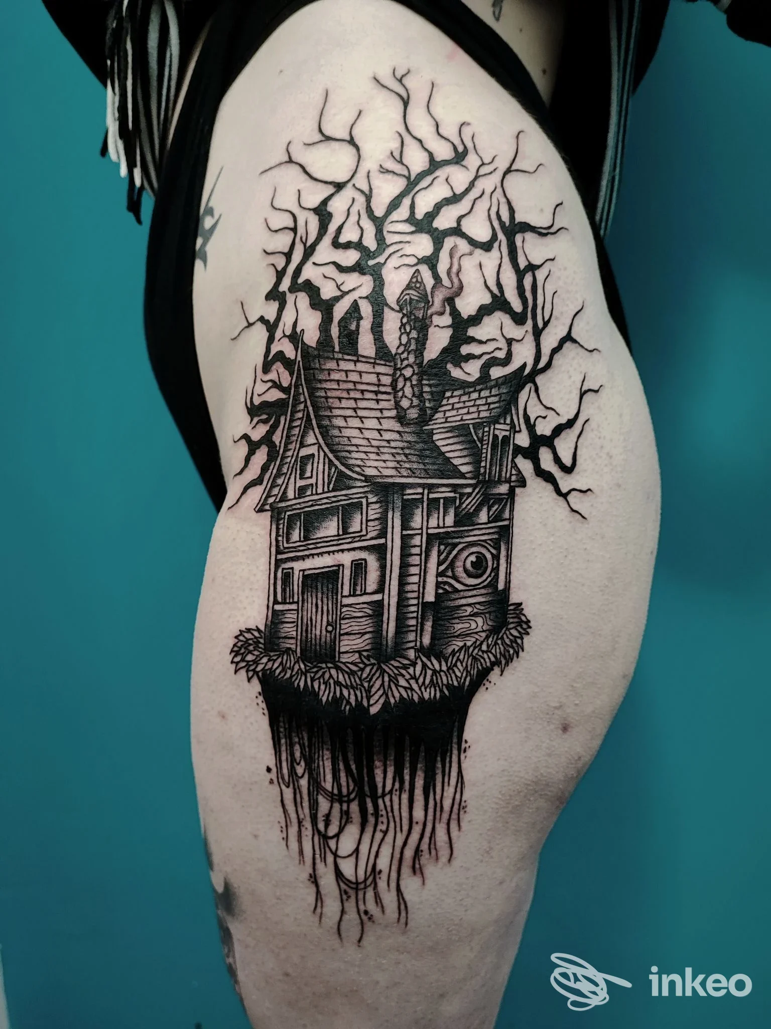 Ampio tatuaggio blackwork di una casa sospesa con radici e rami sul lato della coscia. Opera fotografata per G. COX TATTOO, Catania.