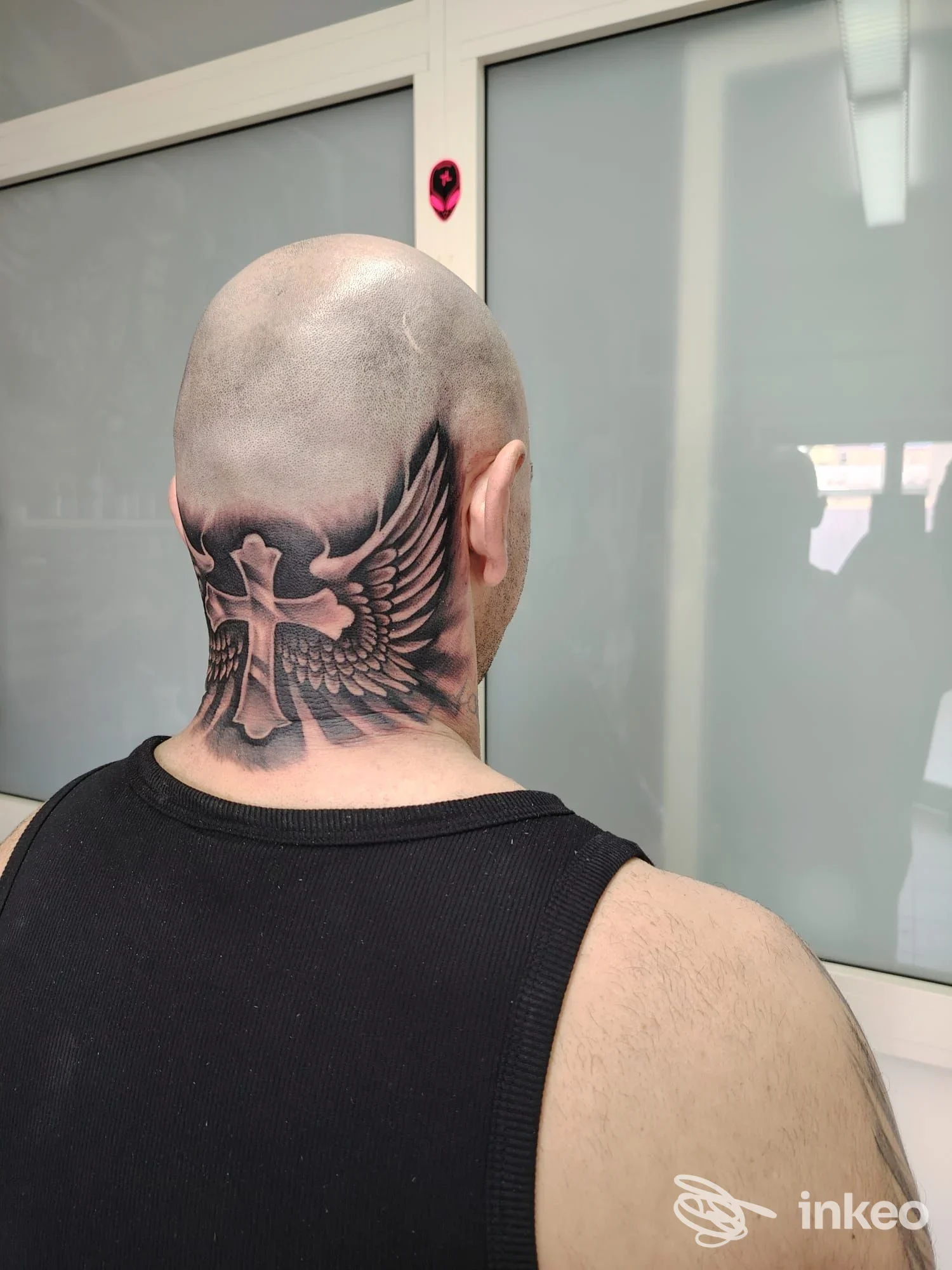 Tatuaggio a croce con ali sulla nuca e parte posteriore della testa, foto fornita da G. P. Project S. R. L., Cefalù.