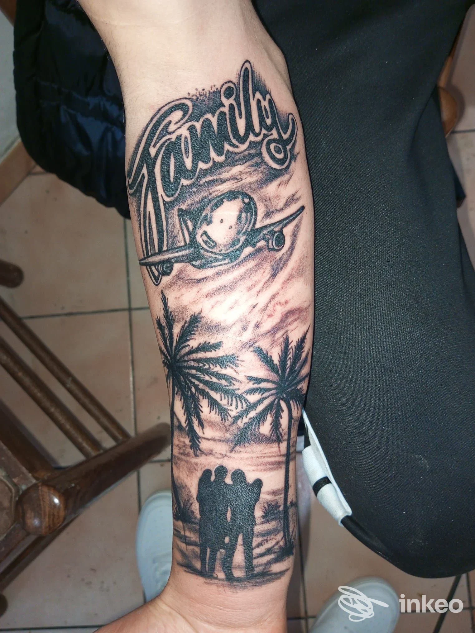 Avambraccio tatuato con la scritta 'Familia', un aeroplano, palme e la sagoma di tre persone. Foto inviata da Giupy Tattoo, Palermo.