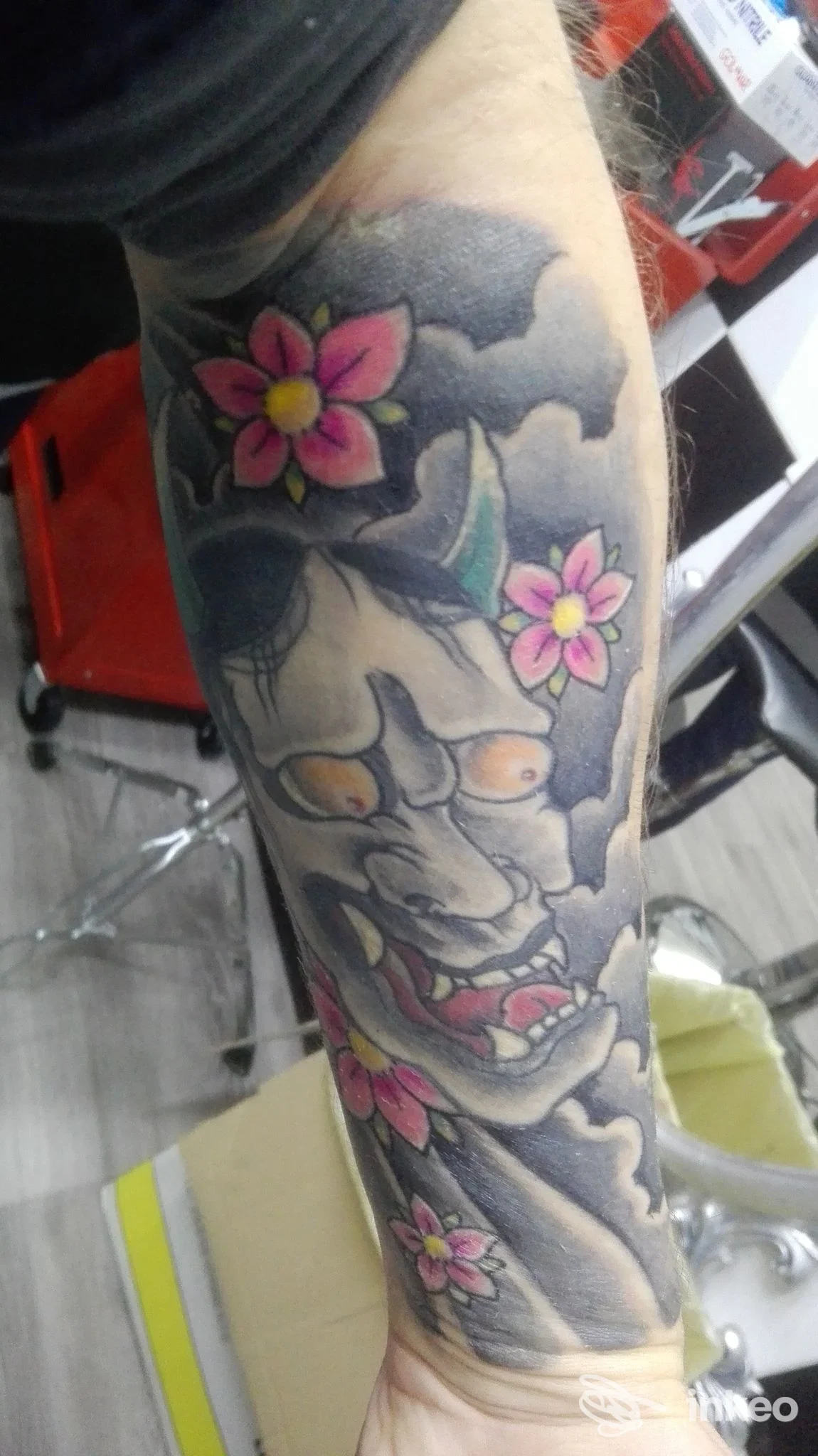 Tatuaggio a manica su avambraccio con maschera e fiori rosa, Giupy Tattoo, Palermo.