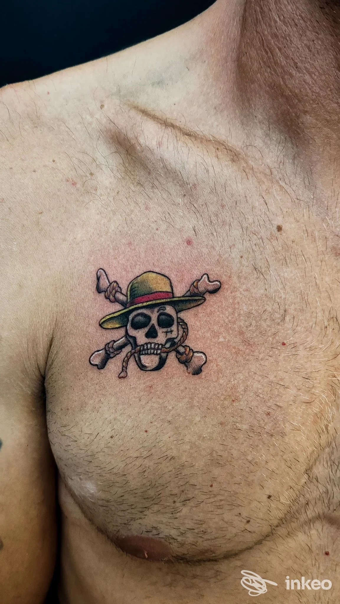 Piccolo tatuaggio di teschio con cappello sul petto di un uomo, realizzato da Fuoriposto Tattoo, Trapani.