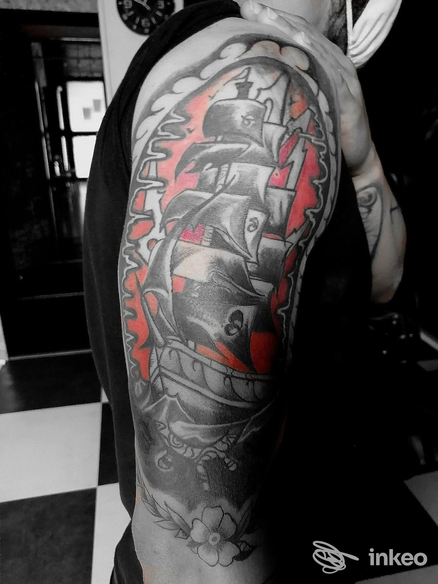 Dettaglio tatuaggio a manica su braccio e spalla con nave a vele e sfondo rosso, foto fornita da GR SKIN INK tattoo studio, Caltagirone.