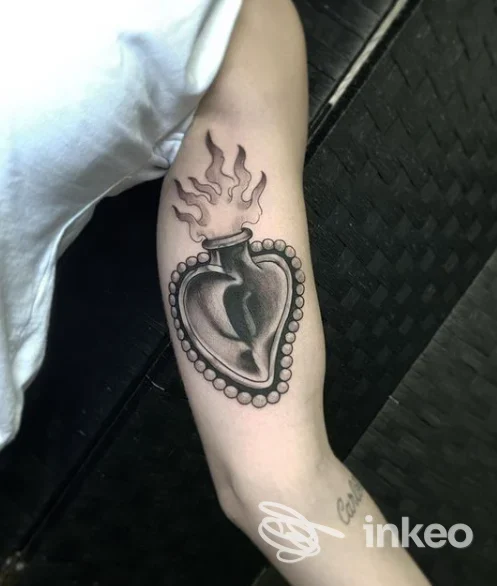 Tatuaggio a forma di cuore con fiamme sull'avambraccio, fotografato presso Garage Tattoo a Catania.