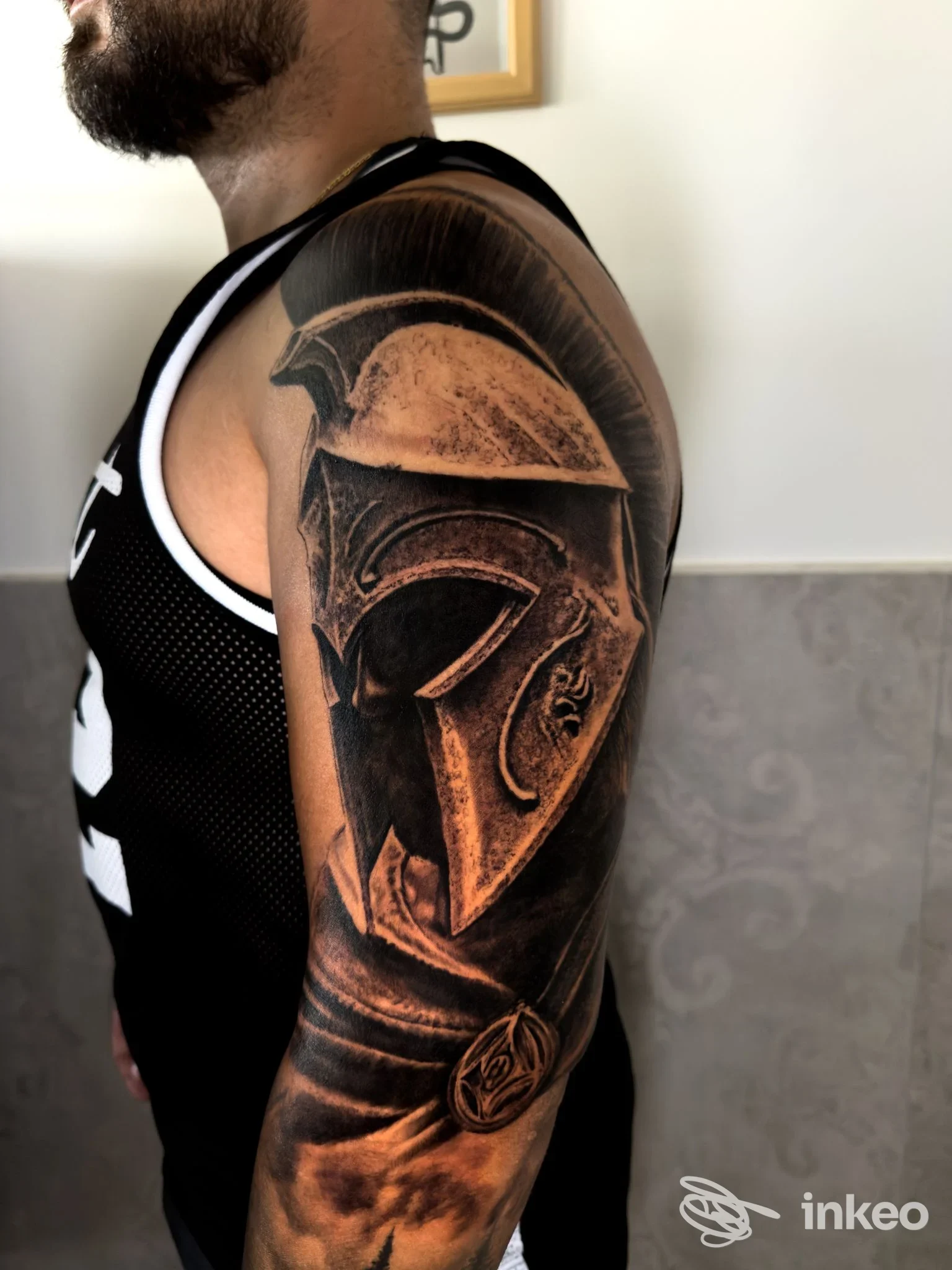 Tatuaggio realistico di elmo spartano sul braccio e spalla, foto fornita da Ink Life Tattoo Studio, Floridia.