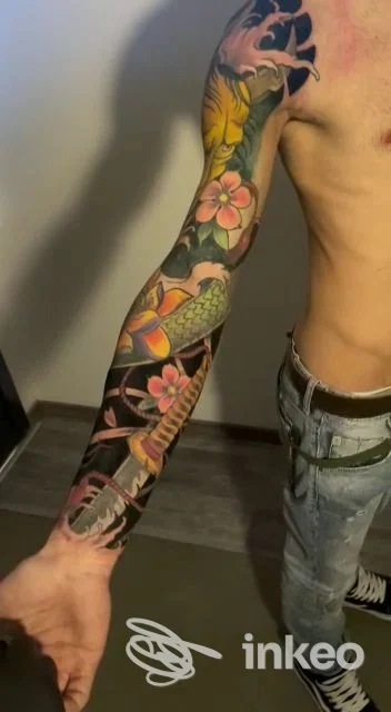 Manica tatuata colorata dalla spalla al polso con carpa e fiori, foto in studio. L'Alfiere Tattoo, Lentini.