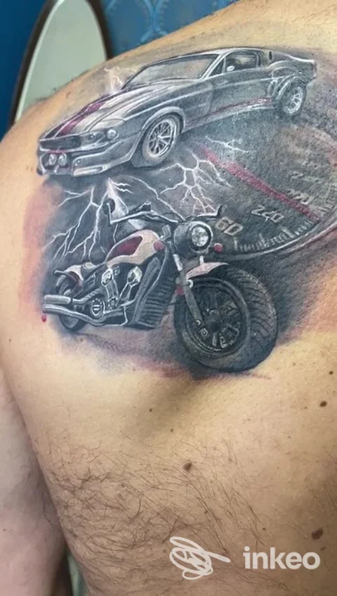 Tattoo realistico su pelle raffigurante una moto nera e una vettura sportiva grigia con sfondo di fulmini, dettagli e ombre ben definiti su spalla/petto sinistro.