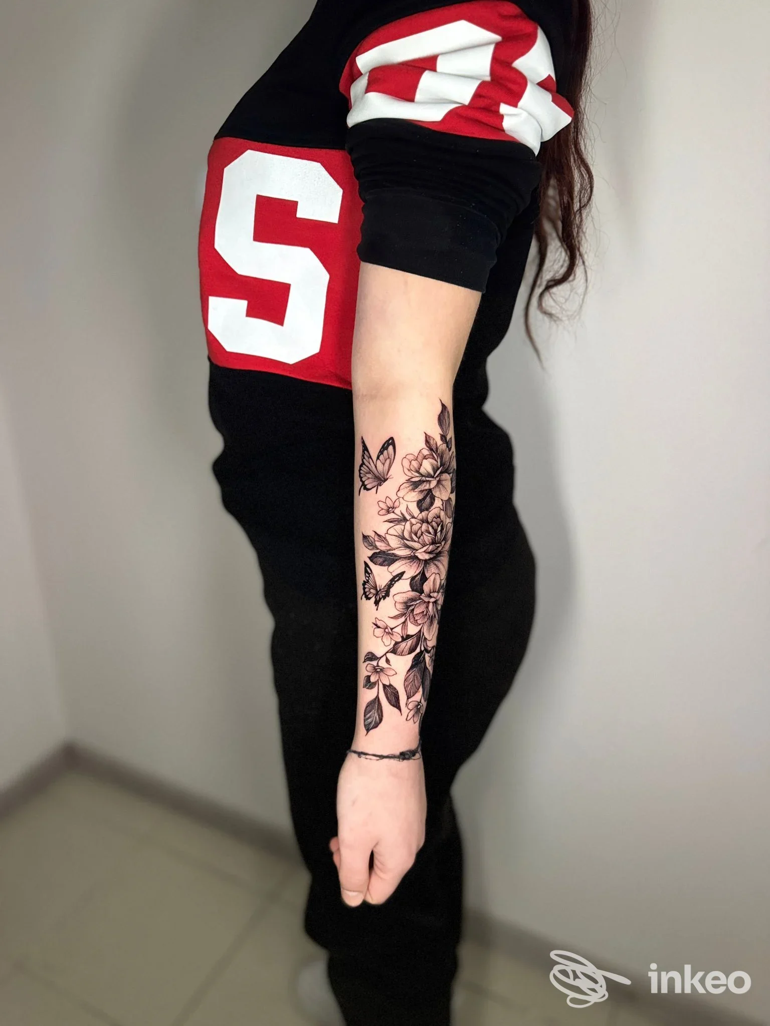 Primo piano del braccio con ampio tatuaggio floreale in nero sull'avambraccio, foto di documentazione per La Fenice Tattoo Ink, Caltanissetta.