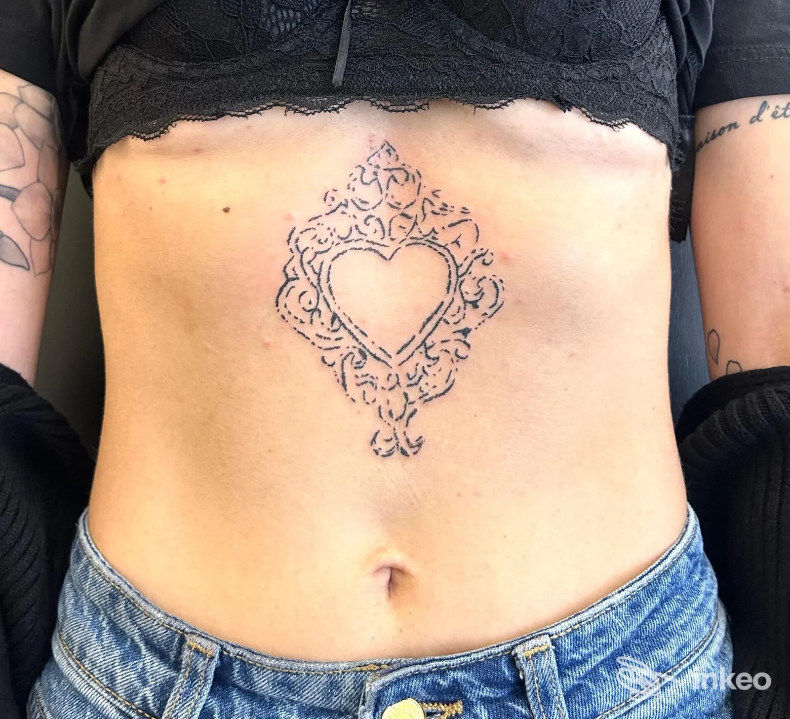 Vista frontale del torso con tatuaggio ornamentale a forma di cuore sullo sterno/alto addome, immagine fornita da Margera Tattoo Studio, Catania.