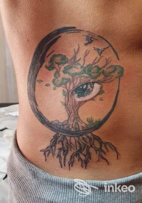 Tatuaggio a tema albero con radici e cerchio, fotografato sul fianco; immagine fornita da Maieutica studio di Yole tattoo art, Palermo.