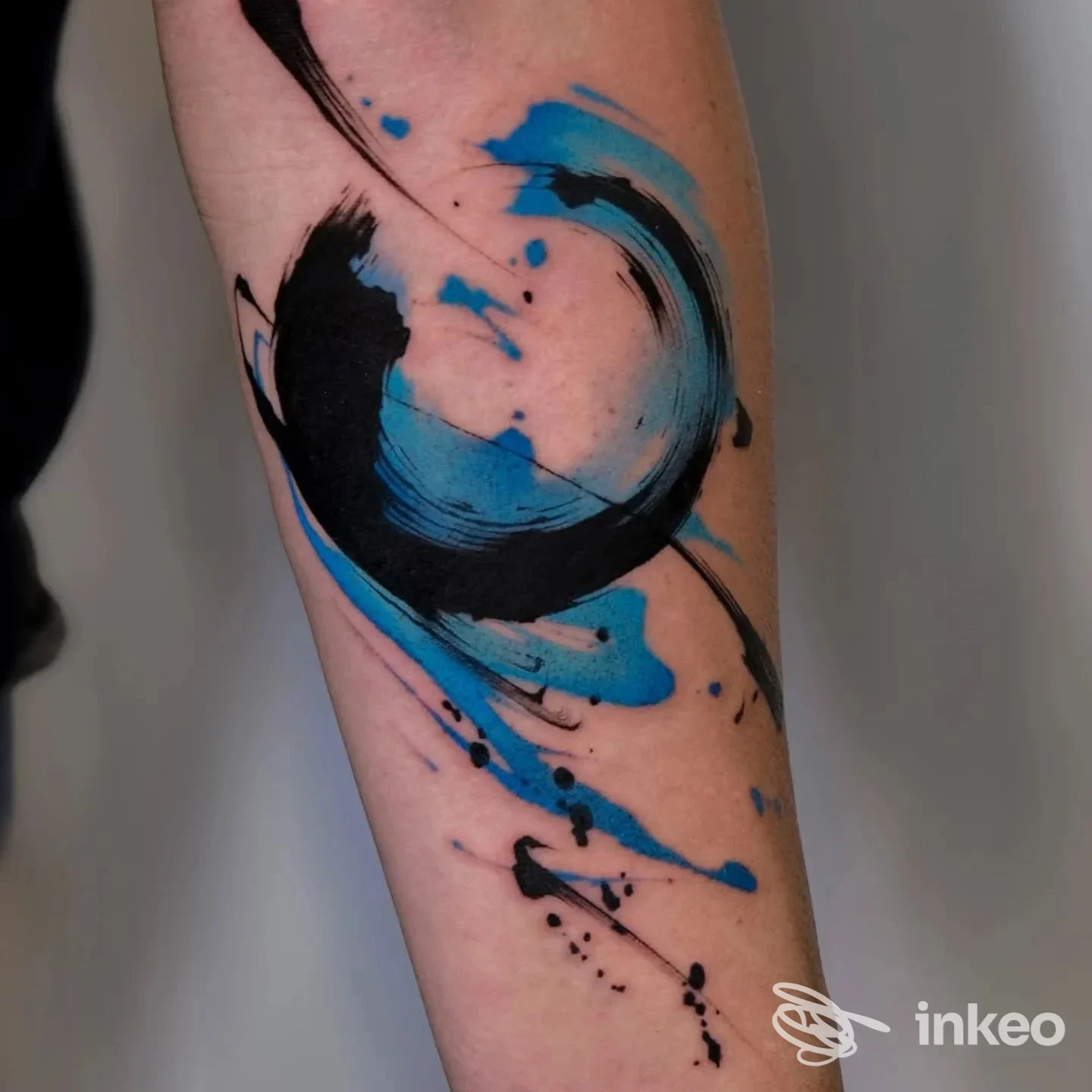 Tatuaggio astratto a pennellate nere e blu sull'avambraccio in luce neutra, lavoro fotografato da Mutazioni Tattoo a Catania.
