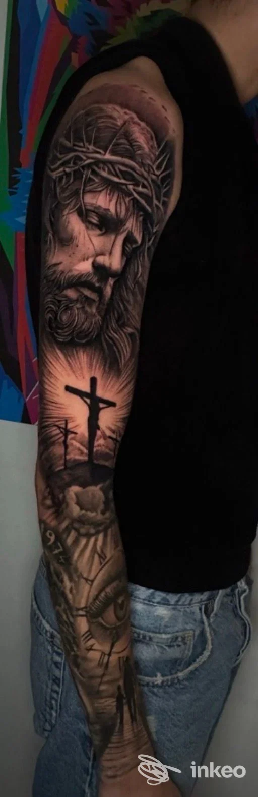 Tatuaggio realistico su braccio con volto di Cristo e tre croci, foto fornita da Nemesis Tattoo Studio, Palermo.
