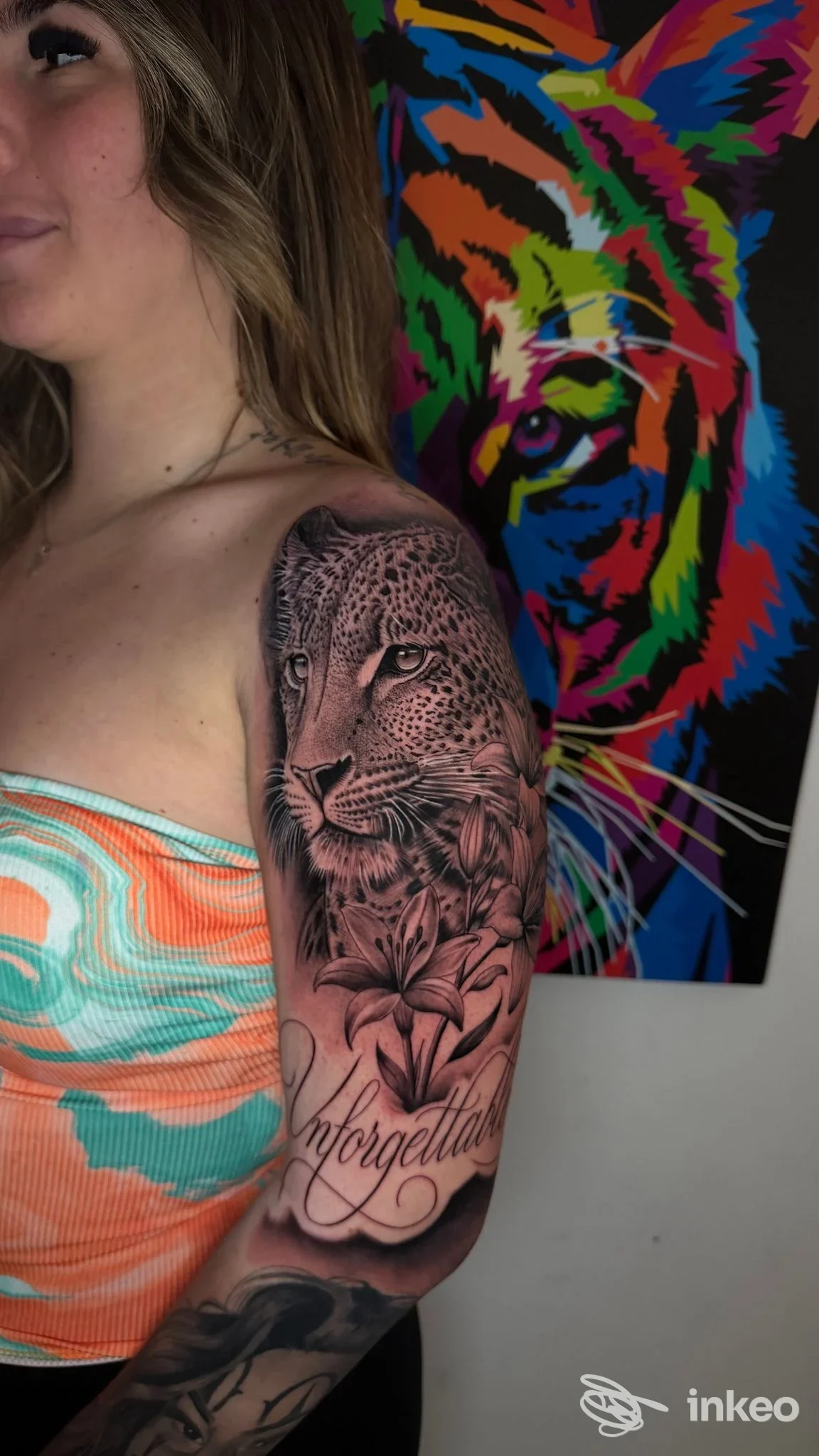 Donna con ampio tatuaggio realistico di leone e fiori sul braccio, foto per Nemesis Tattoo Studio di Carmine Di Domenico, Palermo.