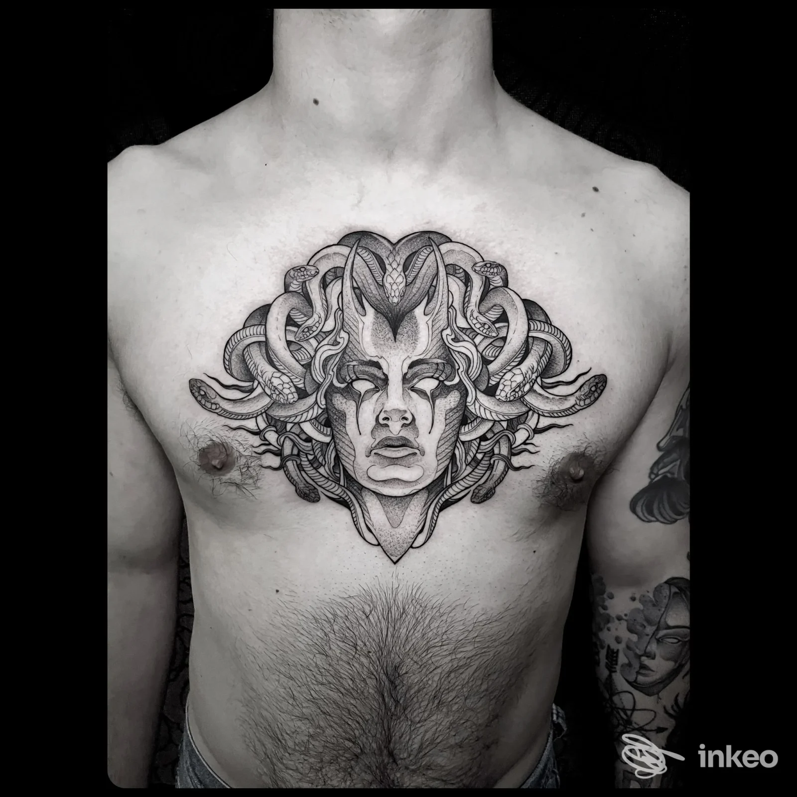 Tatuaggio centrale sul petto raffigurante un volto stilizzato con serpenti, realizzato da Nerho Tattoo a Palermo.