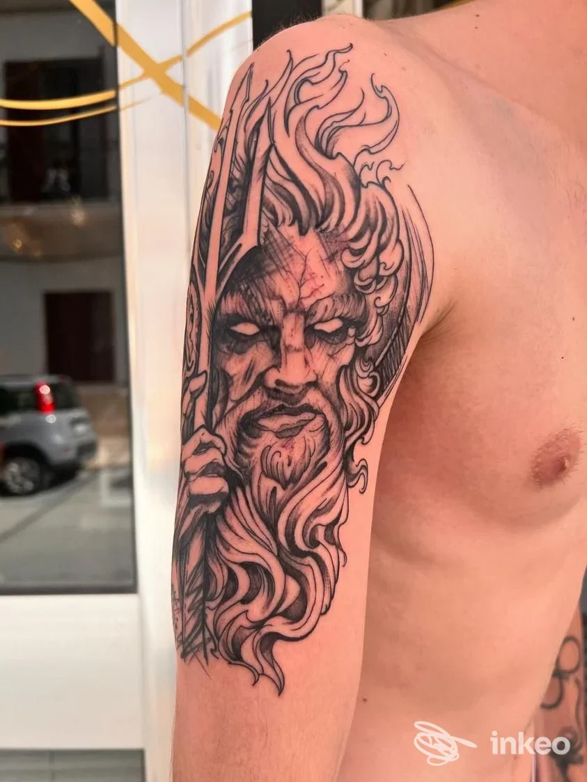 Tatuaggio nero su spalla e braccio con volto mitologico e tridente, opera eseguita da Psych tattoo a Castellammare del Golfo.