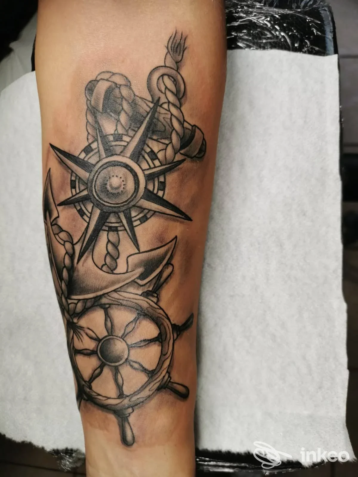 Tatuaggio nautico in bianco e nero con bussola, corda annodata e timone sull'avambraccio. Pyxis Art Tattoo, Castelbuono.
