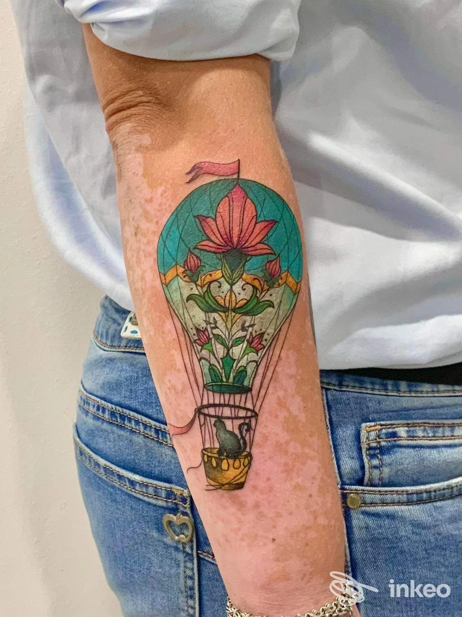 Tatuaggio a forma di mongolfiera decorata con fiori sull'avambraccio, foto fornita da Perfecto Tattoo Studio Vittoria, Vittoria.
