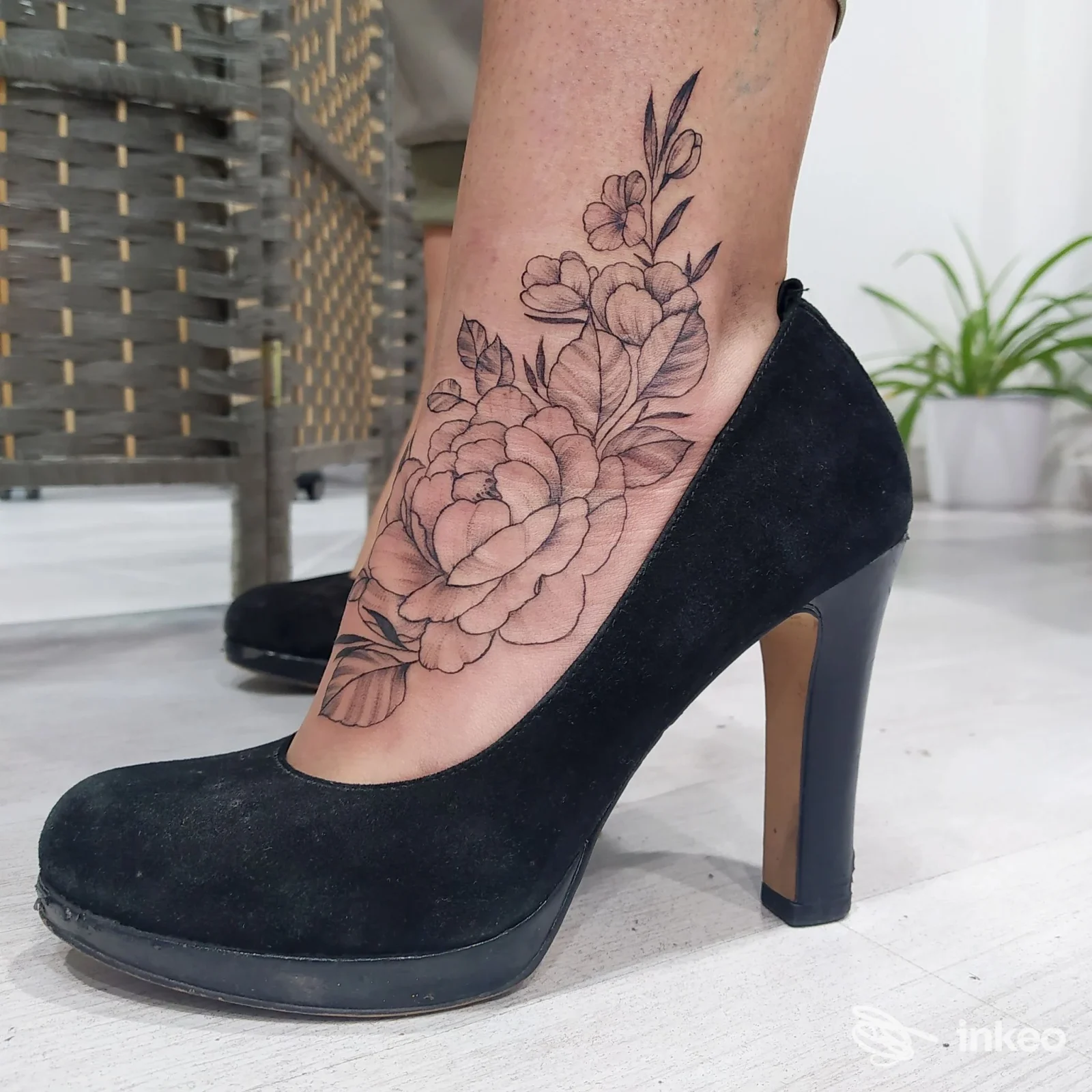 Tatuaggio floreale nero che decora la caviglia e la pianta del piede, fotografia dello studio Perfecto Tattoo Studio Vittoria, Vittoria.