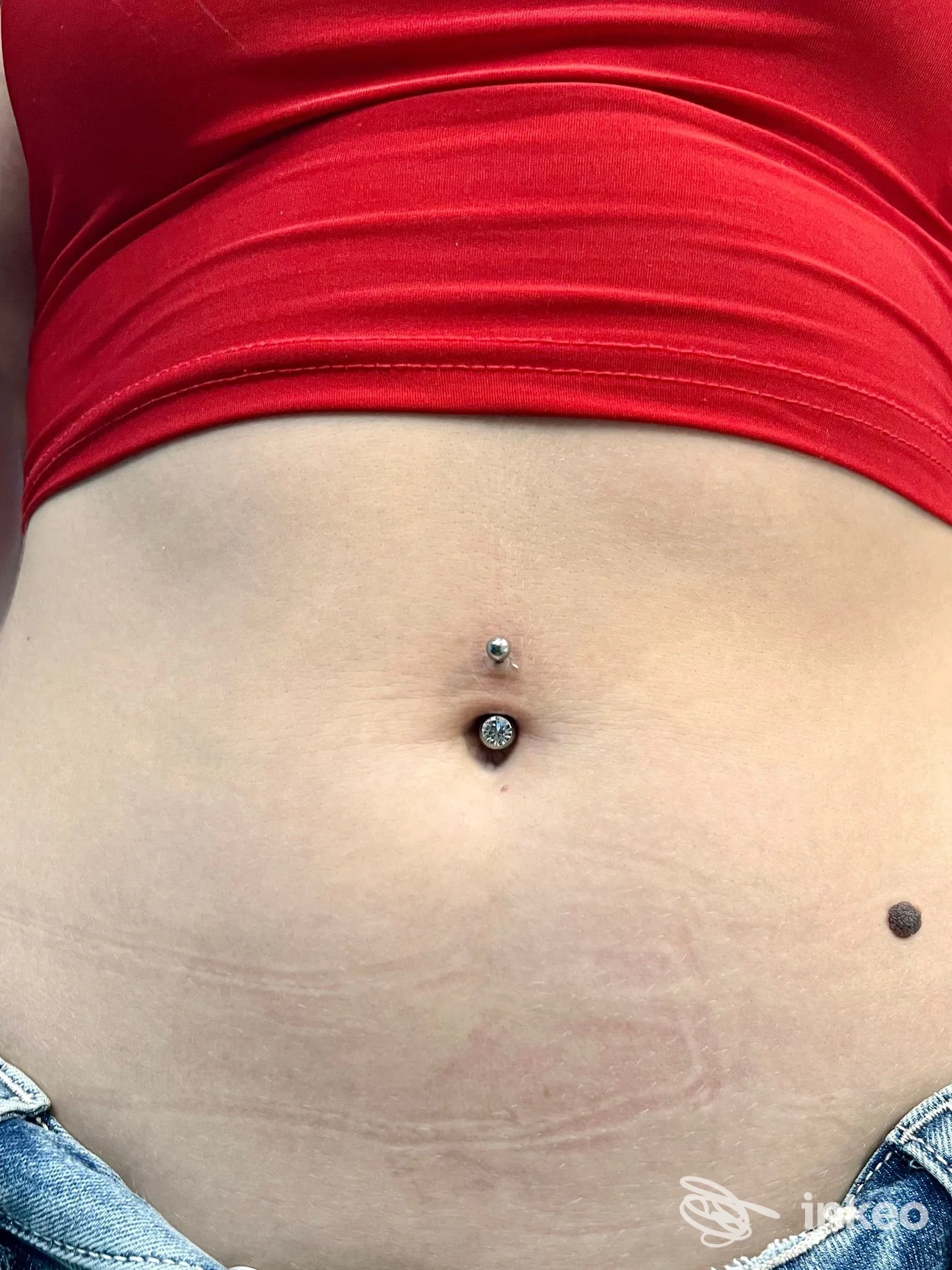 Primo piano di un piercing all'ombelico su addome femminile, Piercing house presso Vanity Mara, Sciacca.