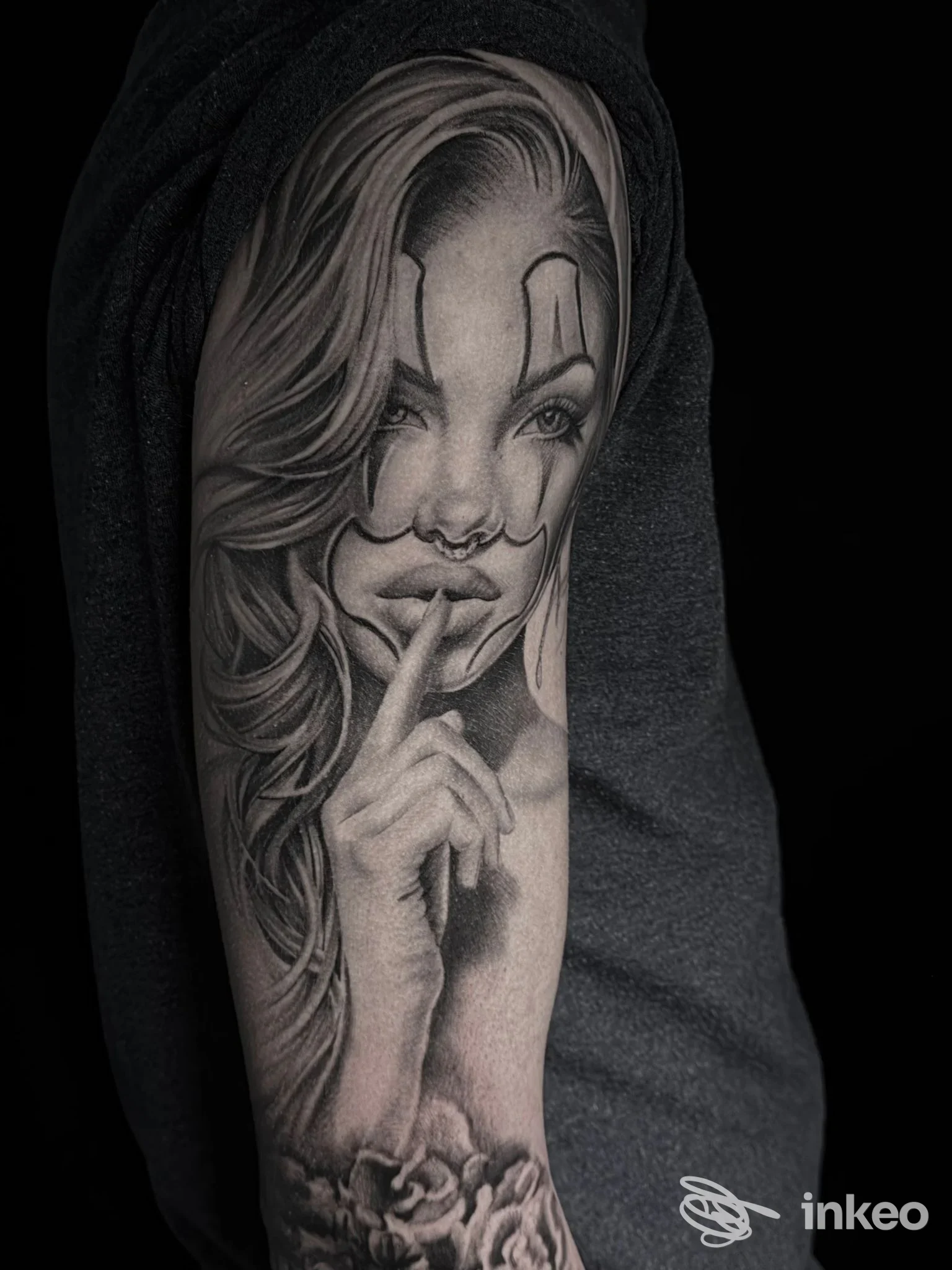Tatuaggio black & grey su braccio con volto femminile e gesto del silenzio — PirrOne Tattoo, Caltanissetta.