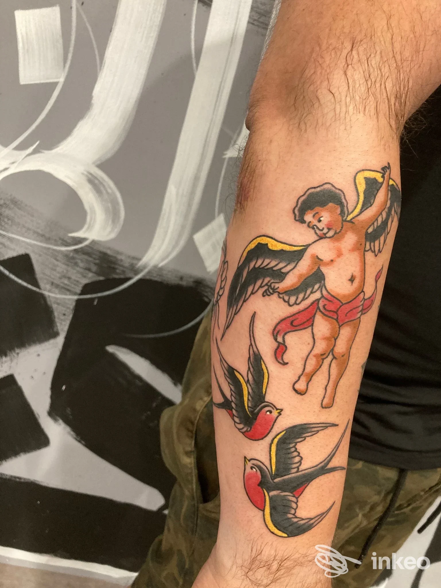 Tatuaggio su avambraccio con cherubino e due rondini, Smith Tattoo Shop Catania.